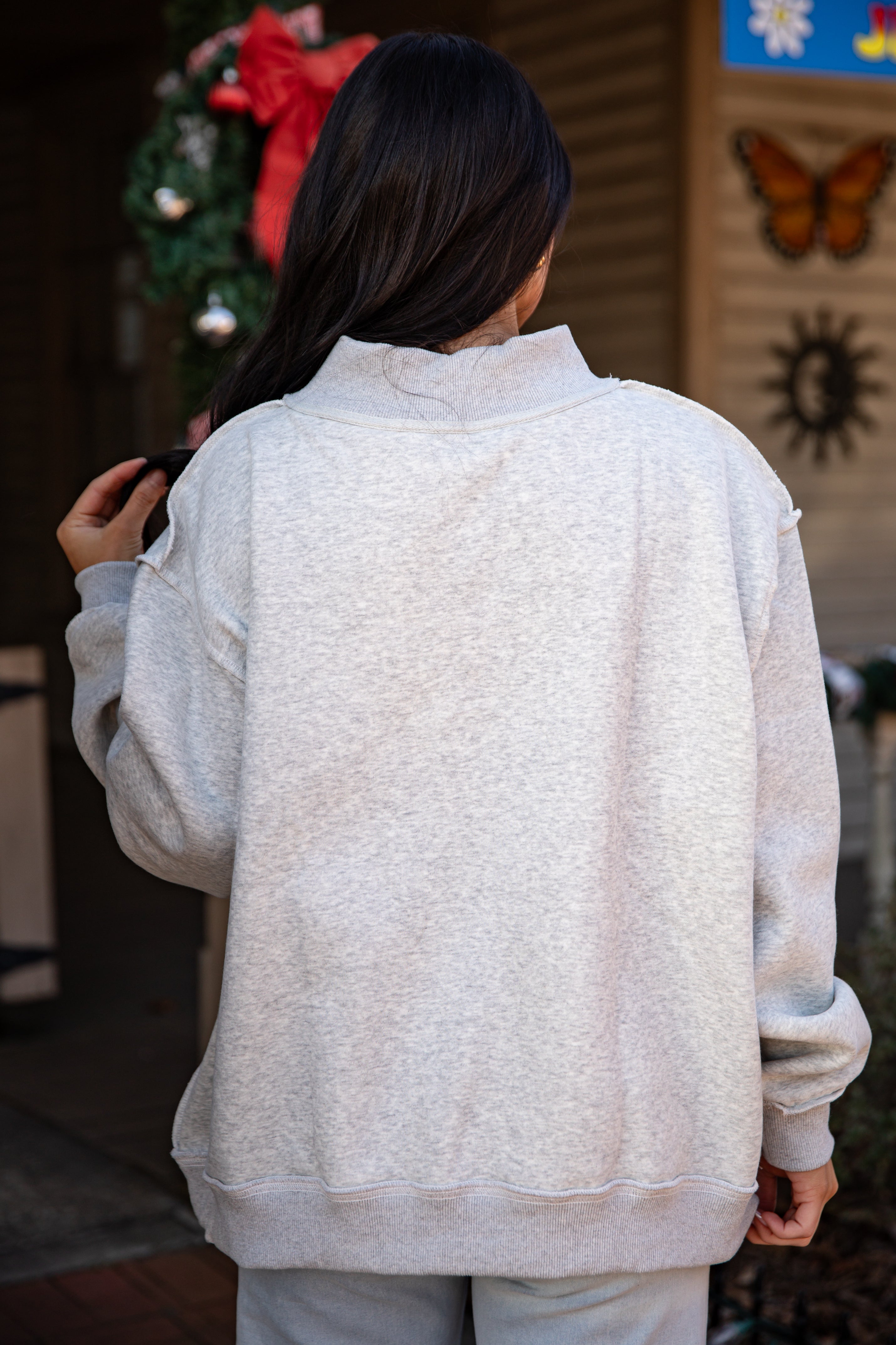 Person wearing a light gray sweatshirt with a decorative background