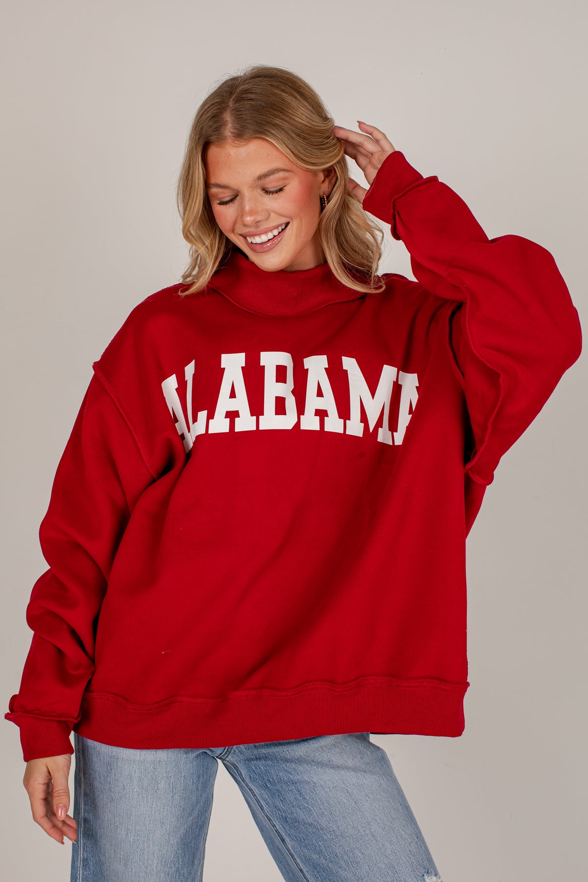 A woman wearing a red oversized sweatshirt with &