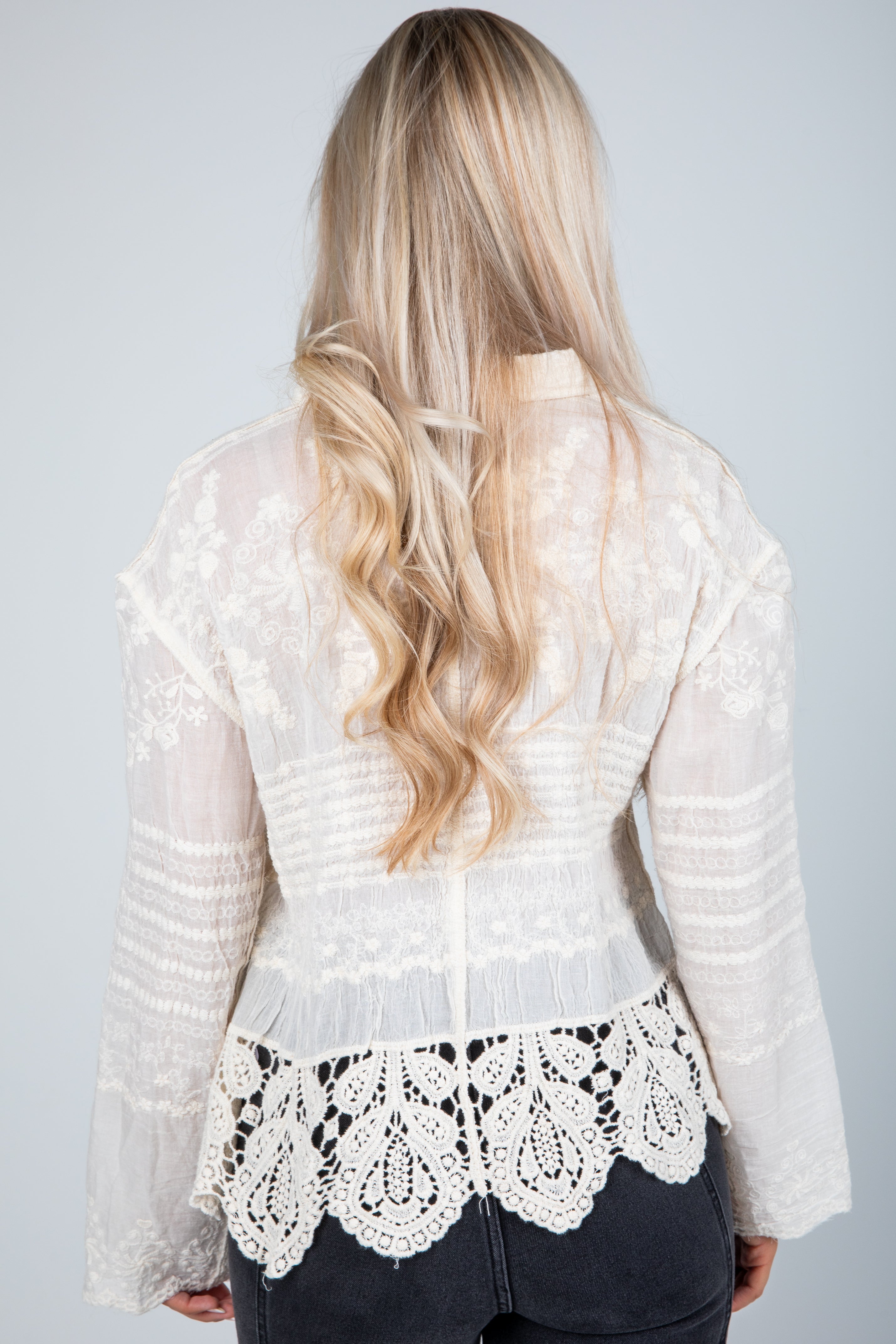 White lace top worn by a person with long blonde hair on a plain background