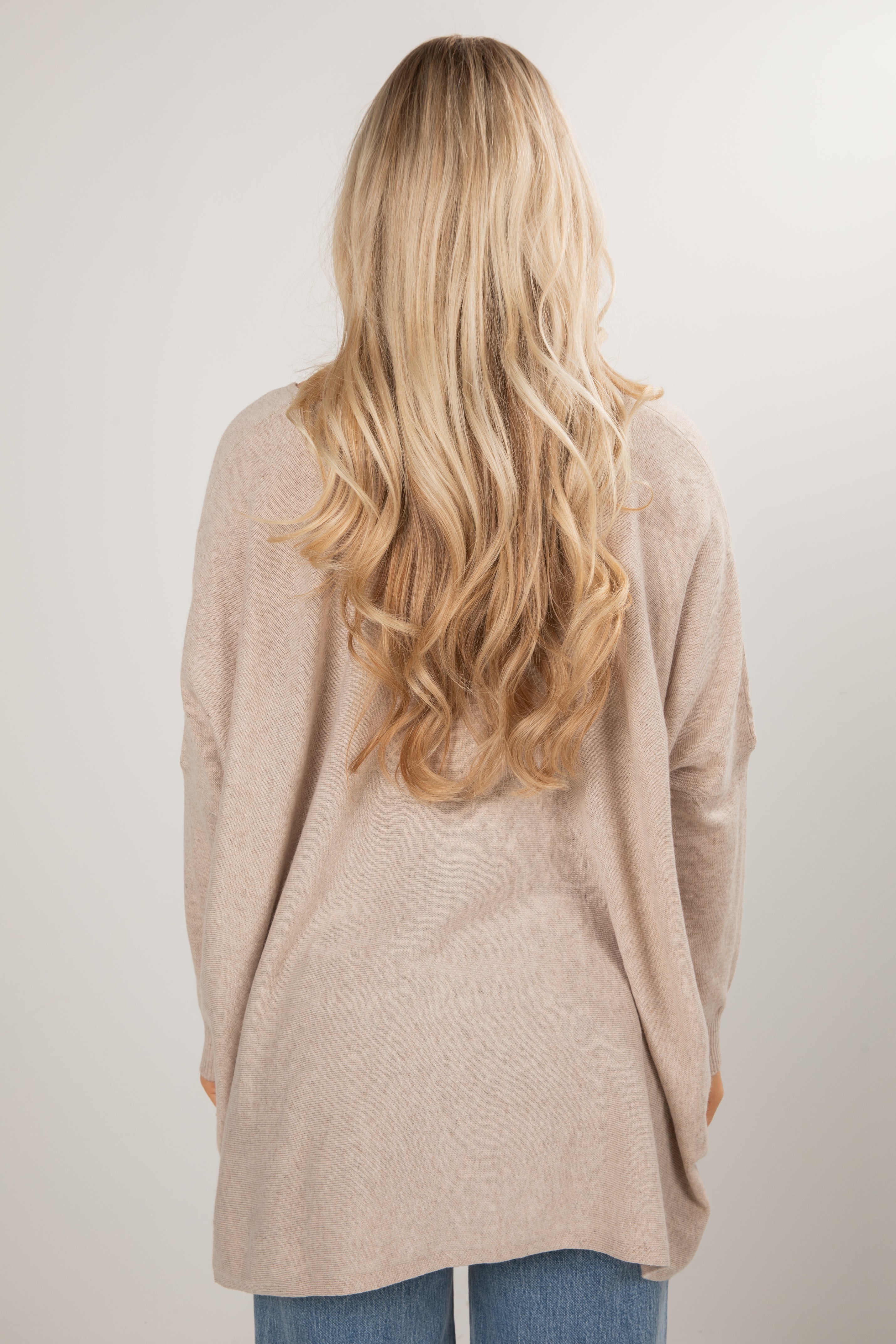Person wearing a beige cardigan with long blonde hair on a plain background