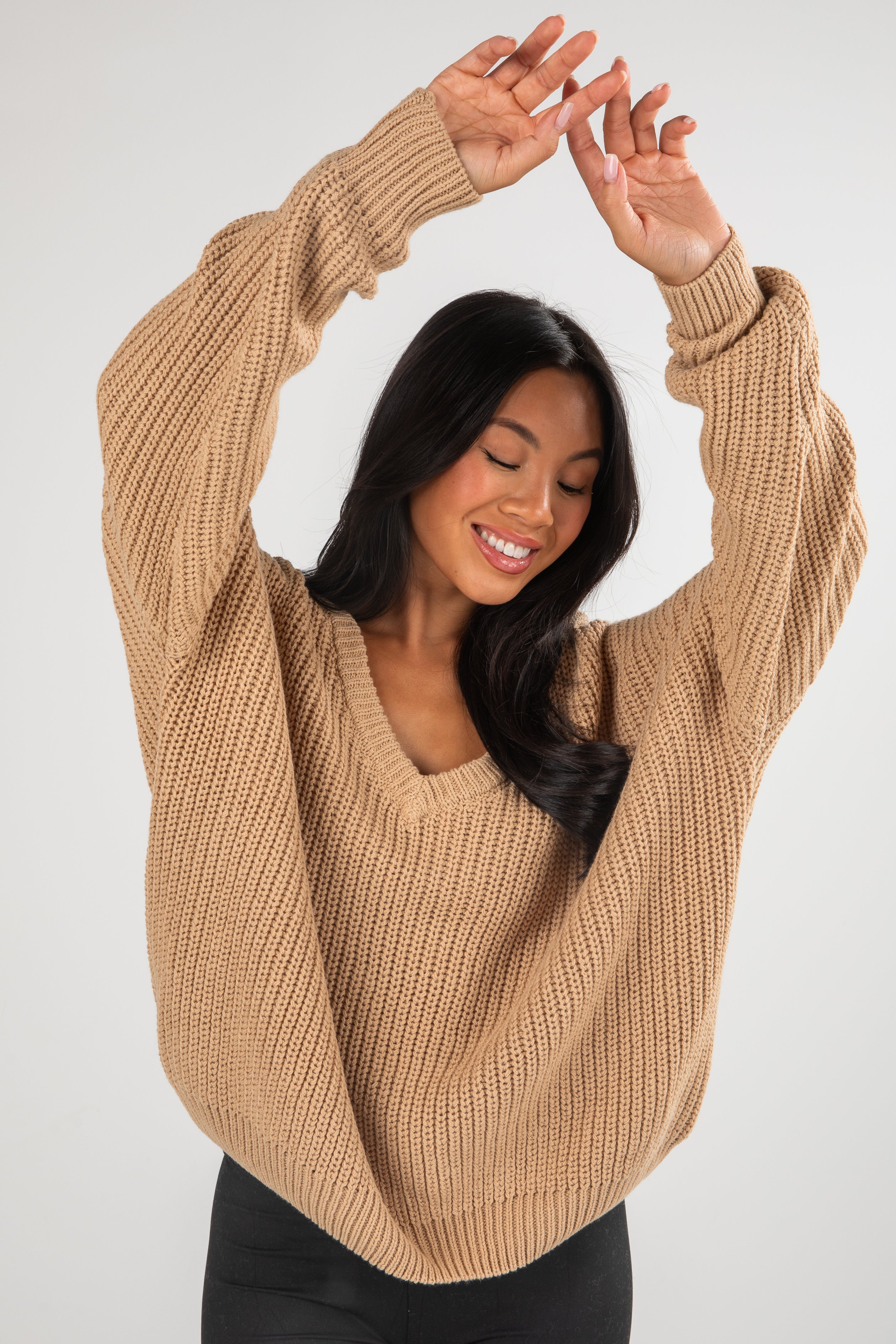Woman wearing a beige sweater against a white background