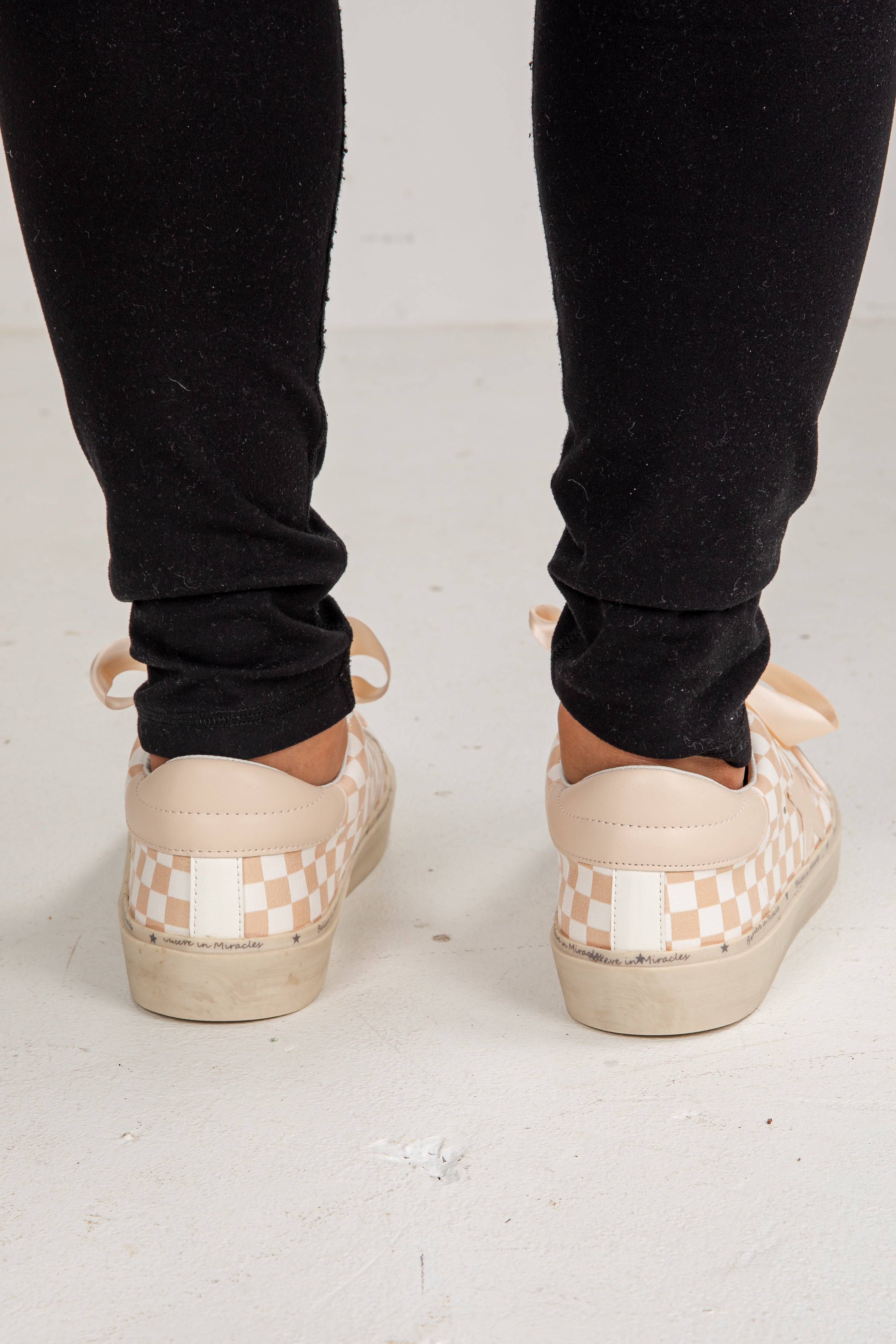 Person wearing checkered platform shoes with black pants on a light background
