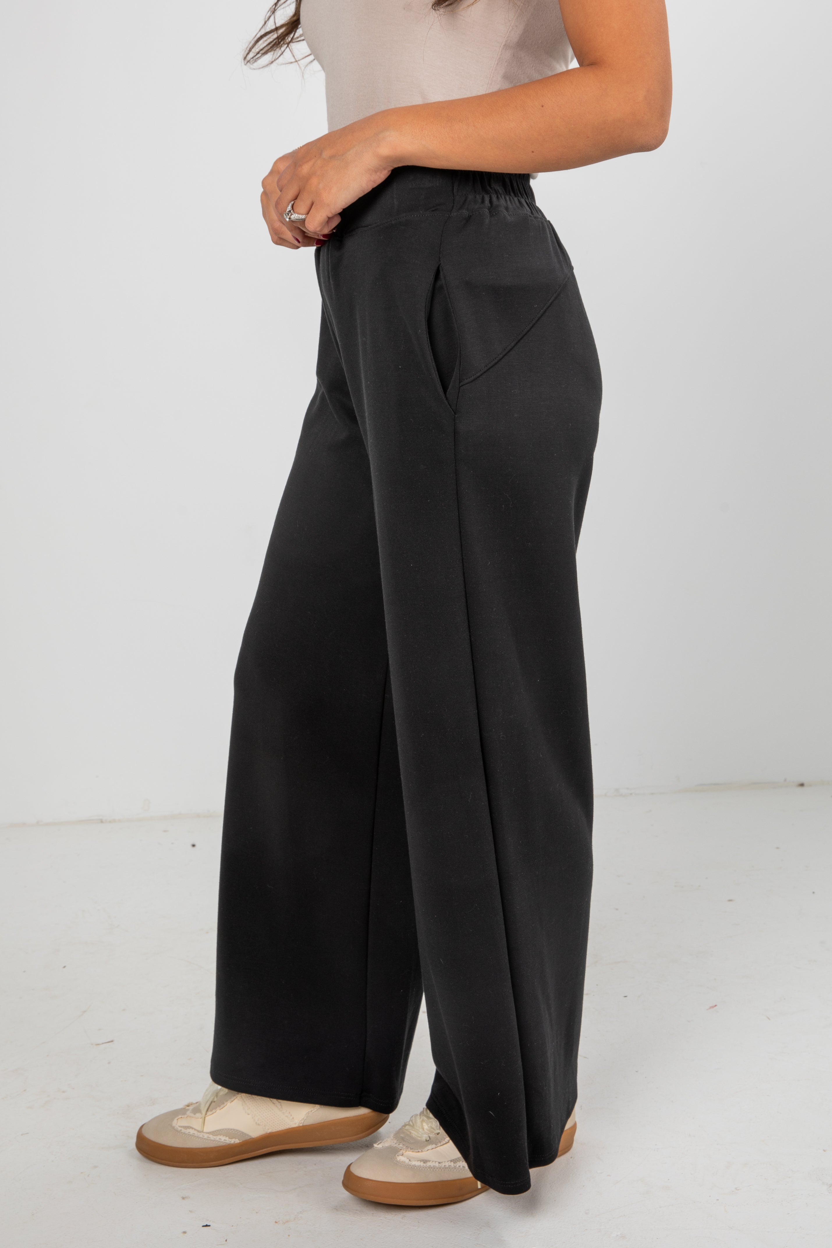 Person wearing black wide-leg pants on a white background