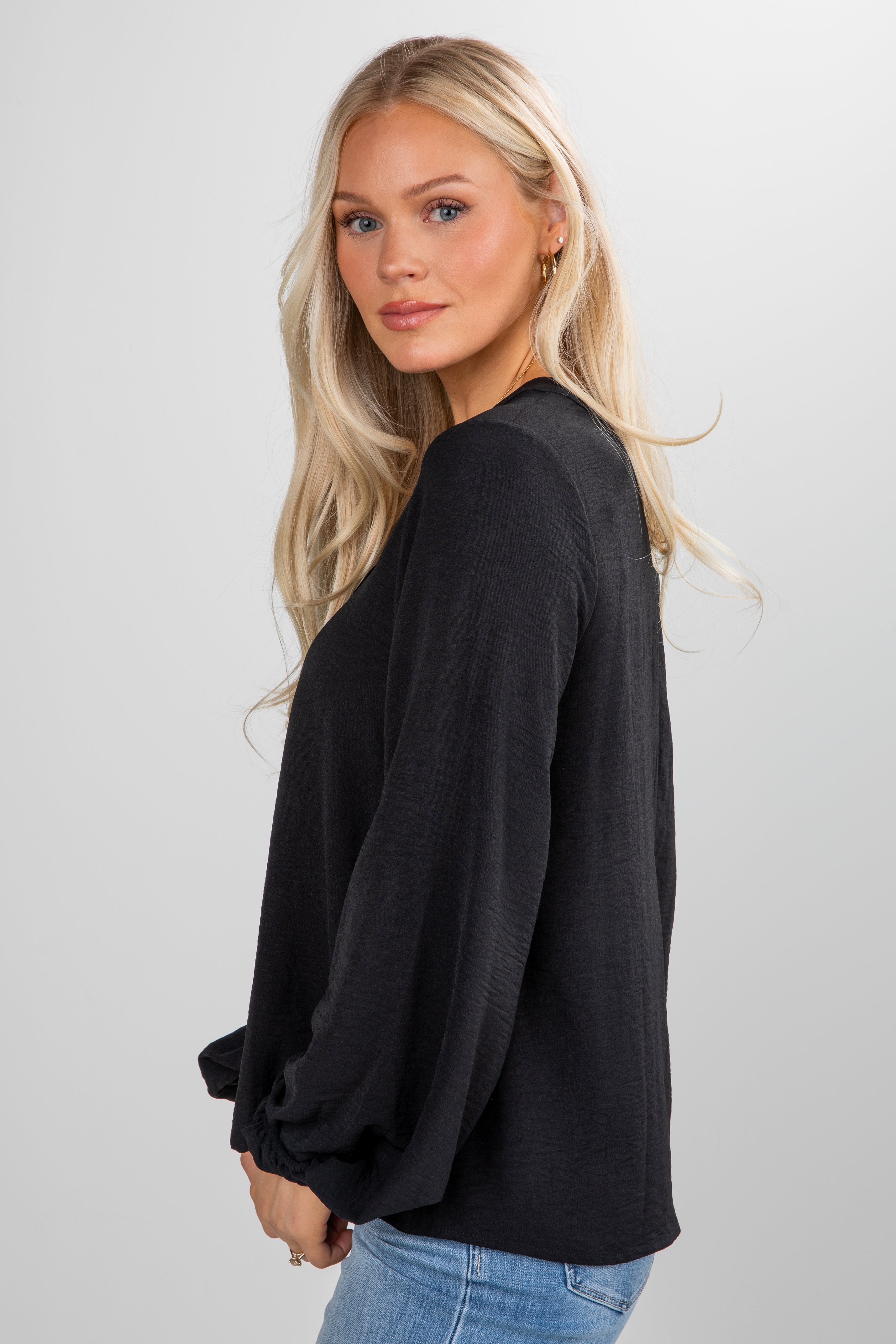 Woman wearing a black oversized sweater against a plain background
