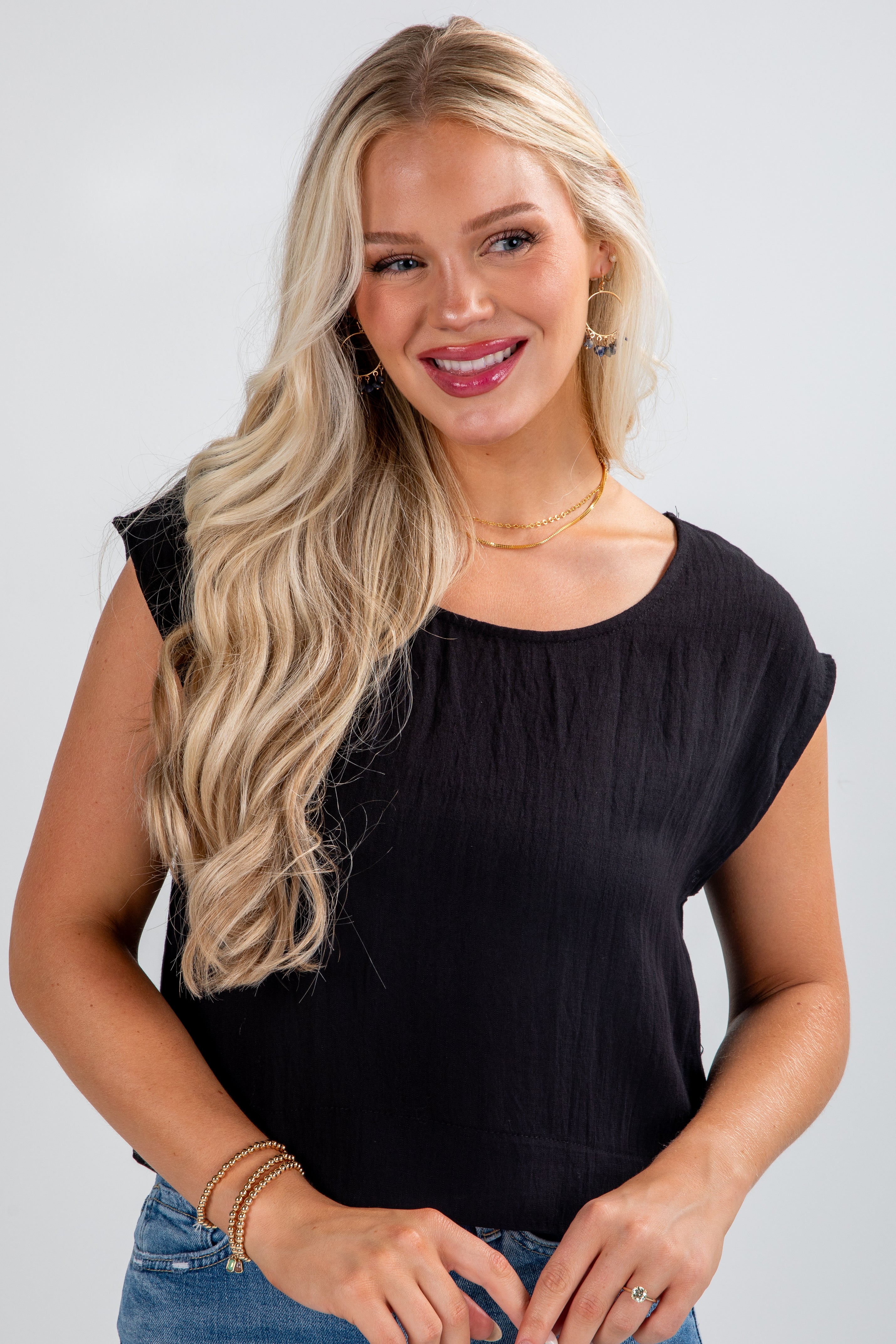 Woman wearing a black top and blue jeans with a plain background