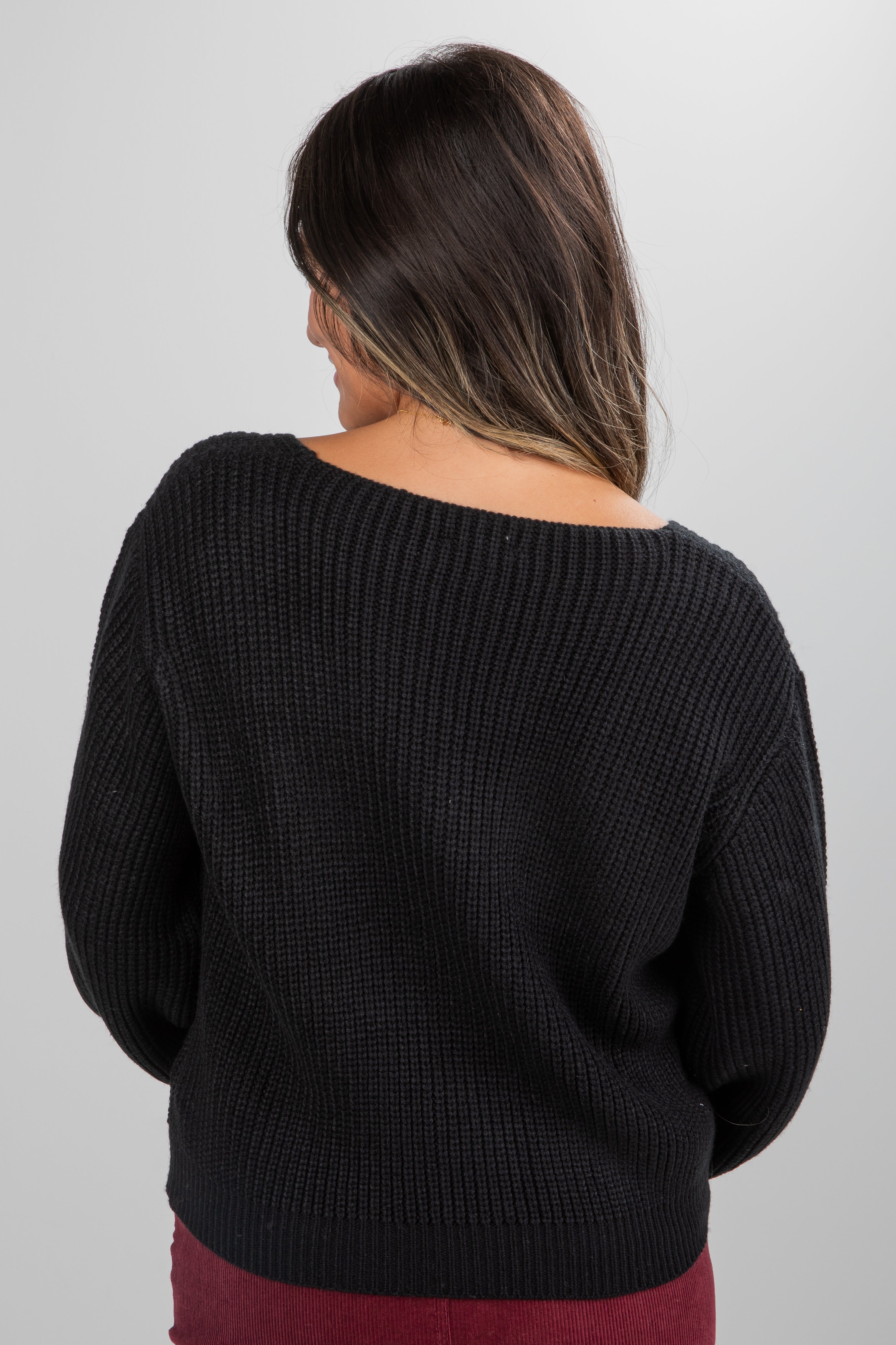 Person wearing a black sweater against a plain background