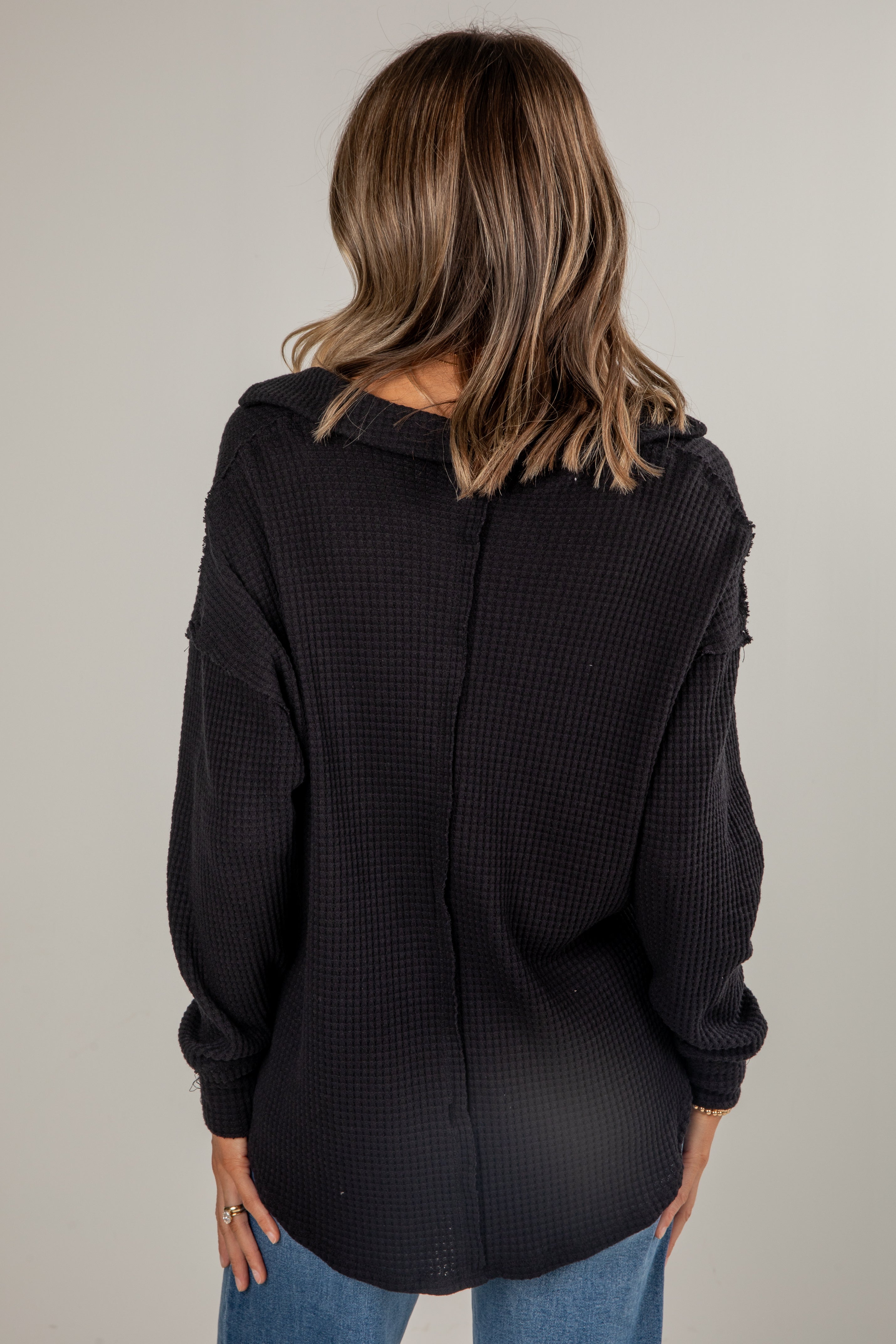 Person wearing a black textured sweater with a neutral background