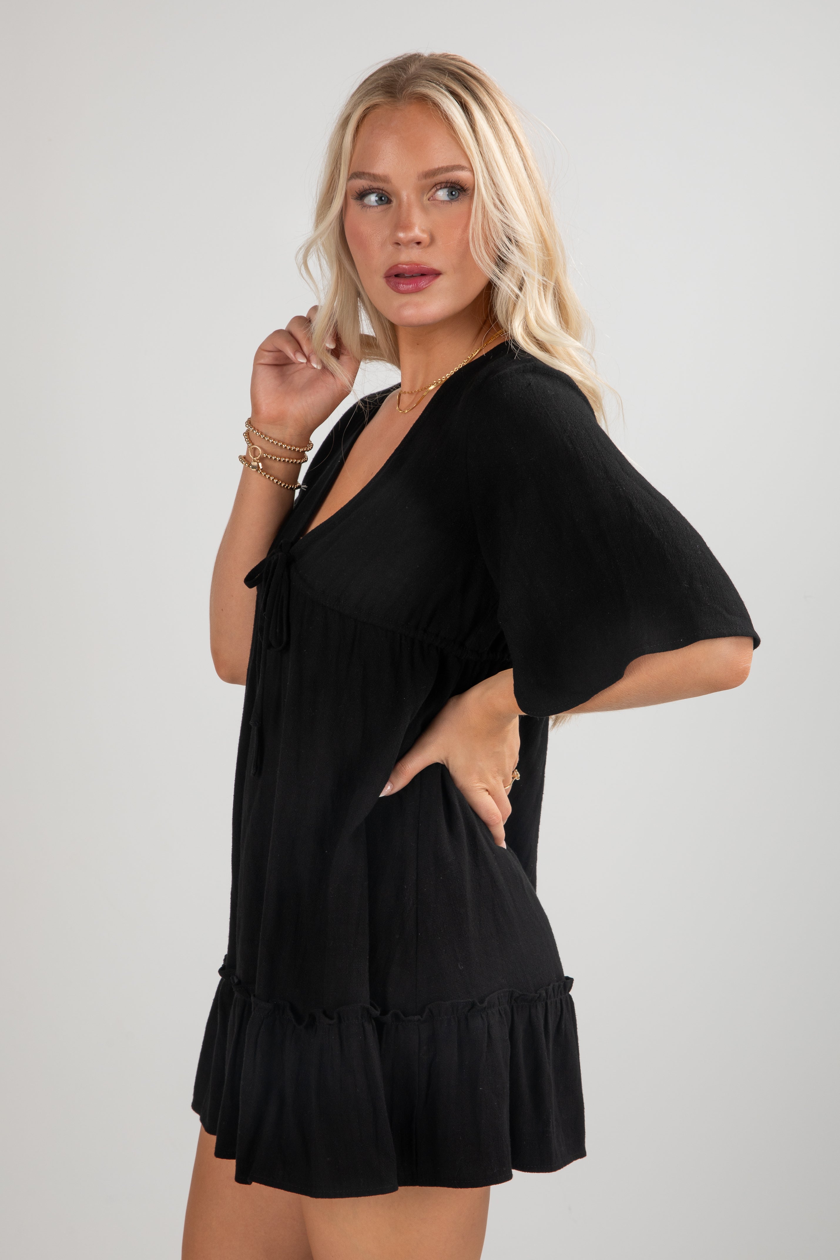 Woman wearing a black dress with ruffled hem on a light gray background