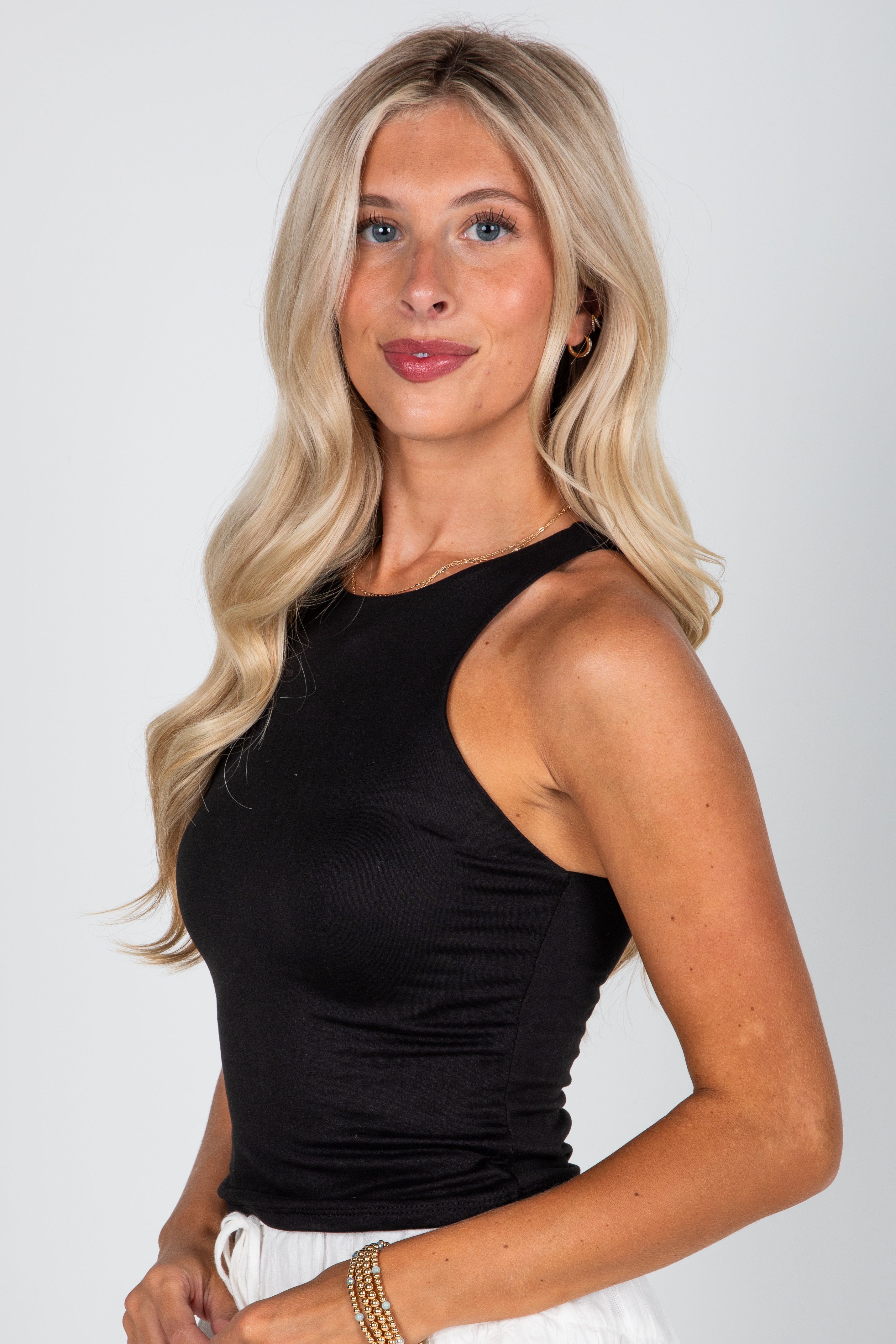 Woman wearing a black sleeveless top against a white background