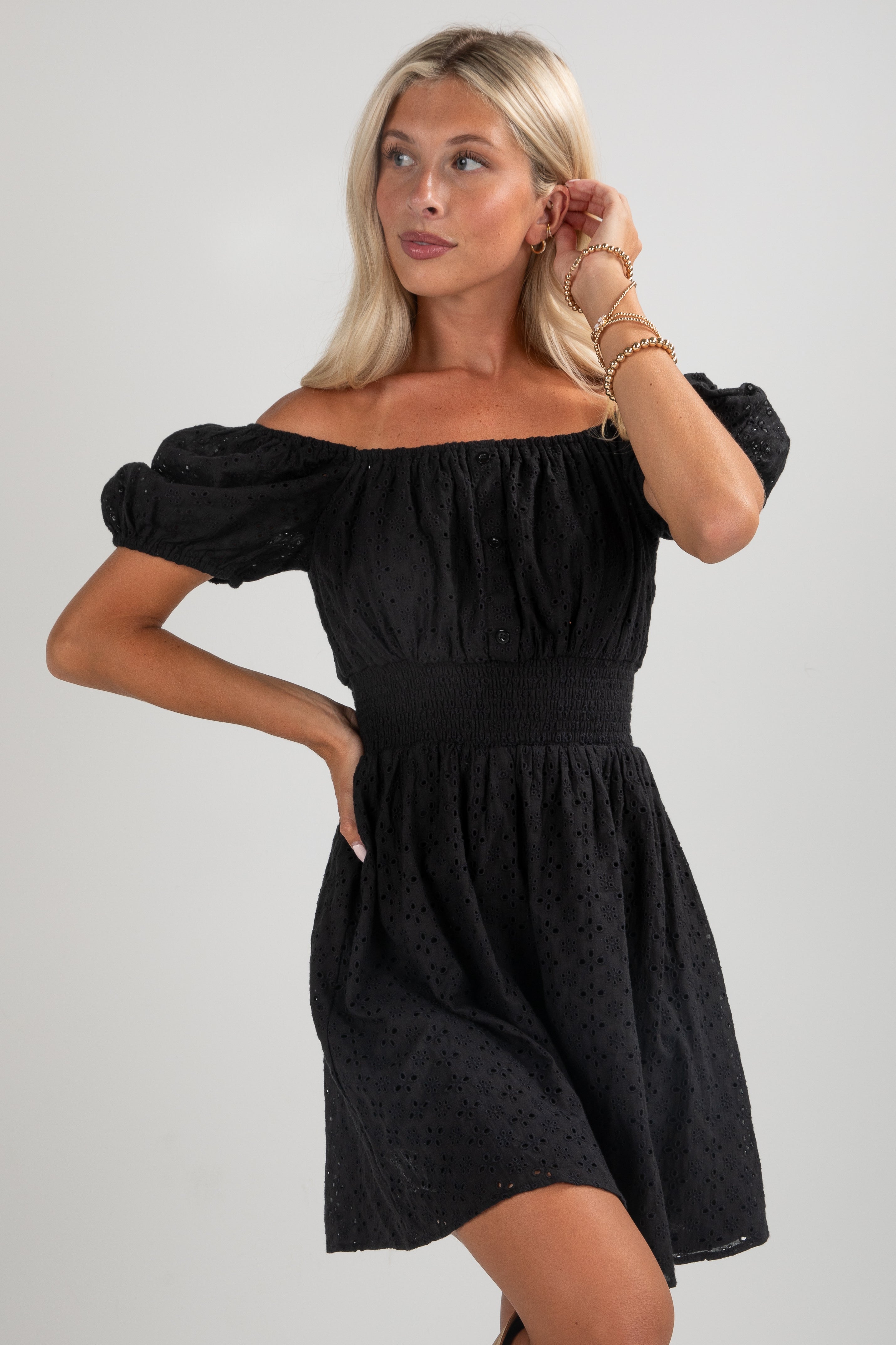 Woman wearing a black off-shoulder dress against a plain background