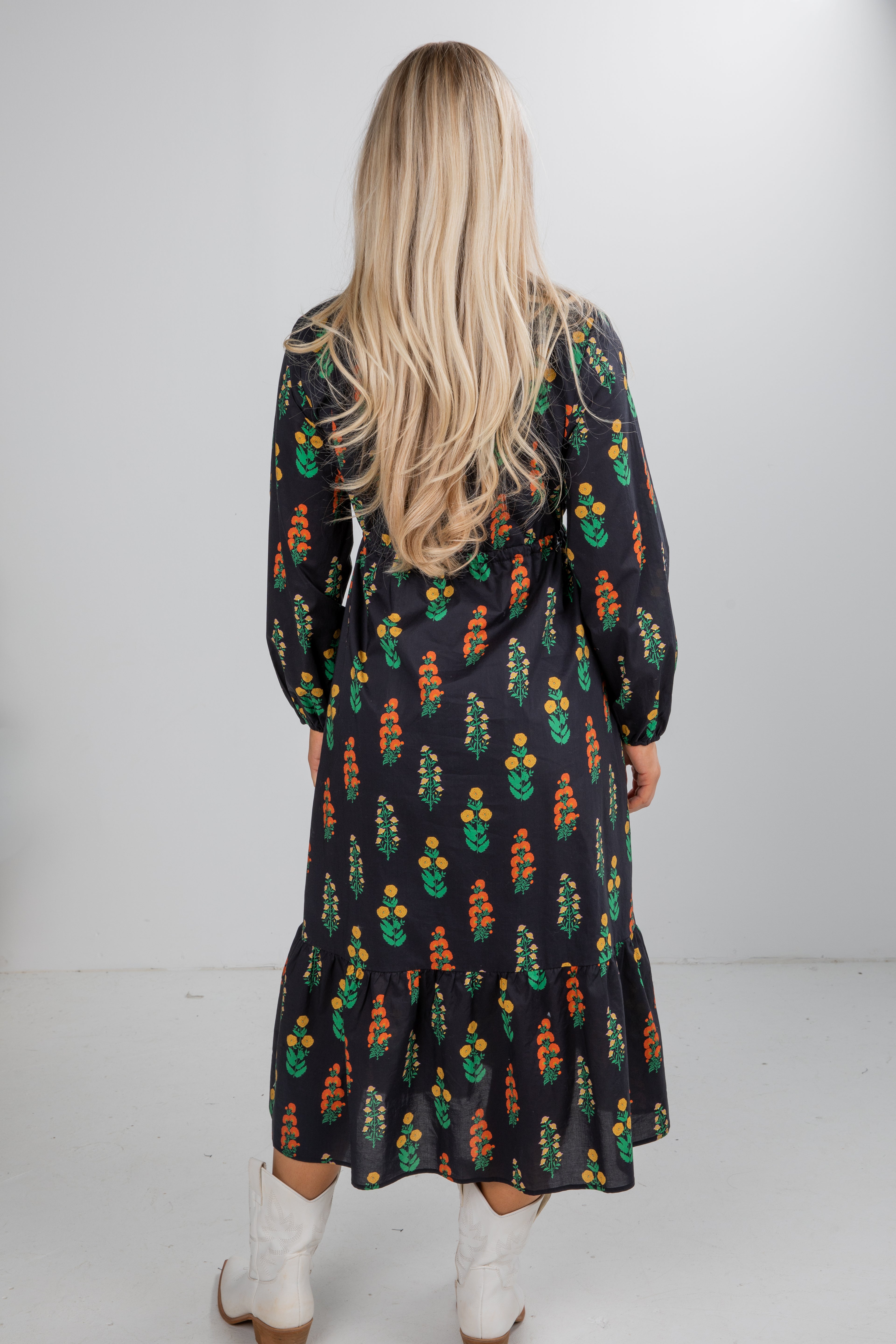 Person wearing a patterned dress with long sleeves and a white background