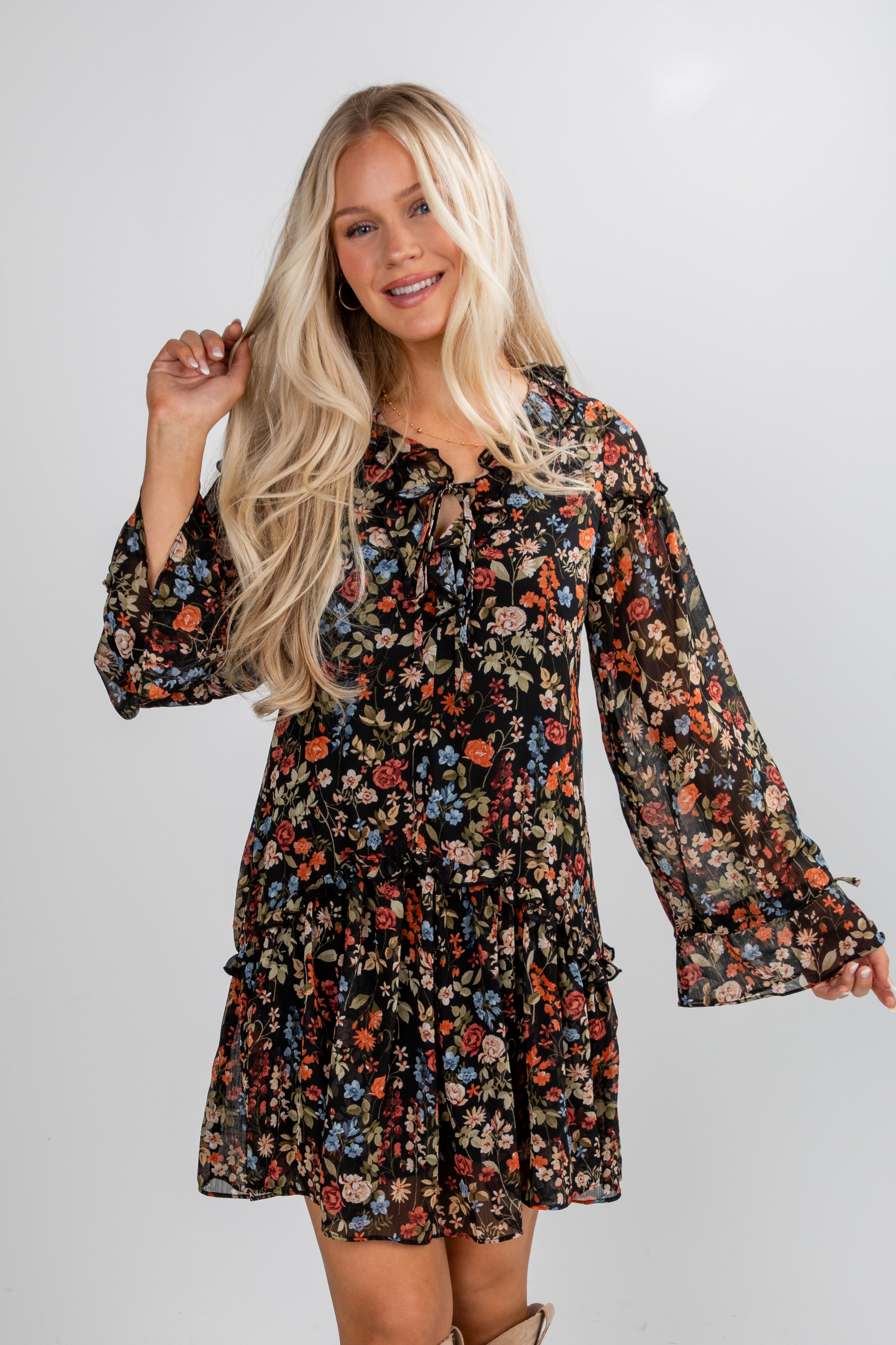 Woman wearing a floral dress with long sleeves on a plain background