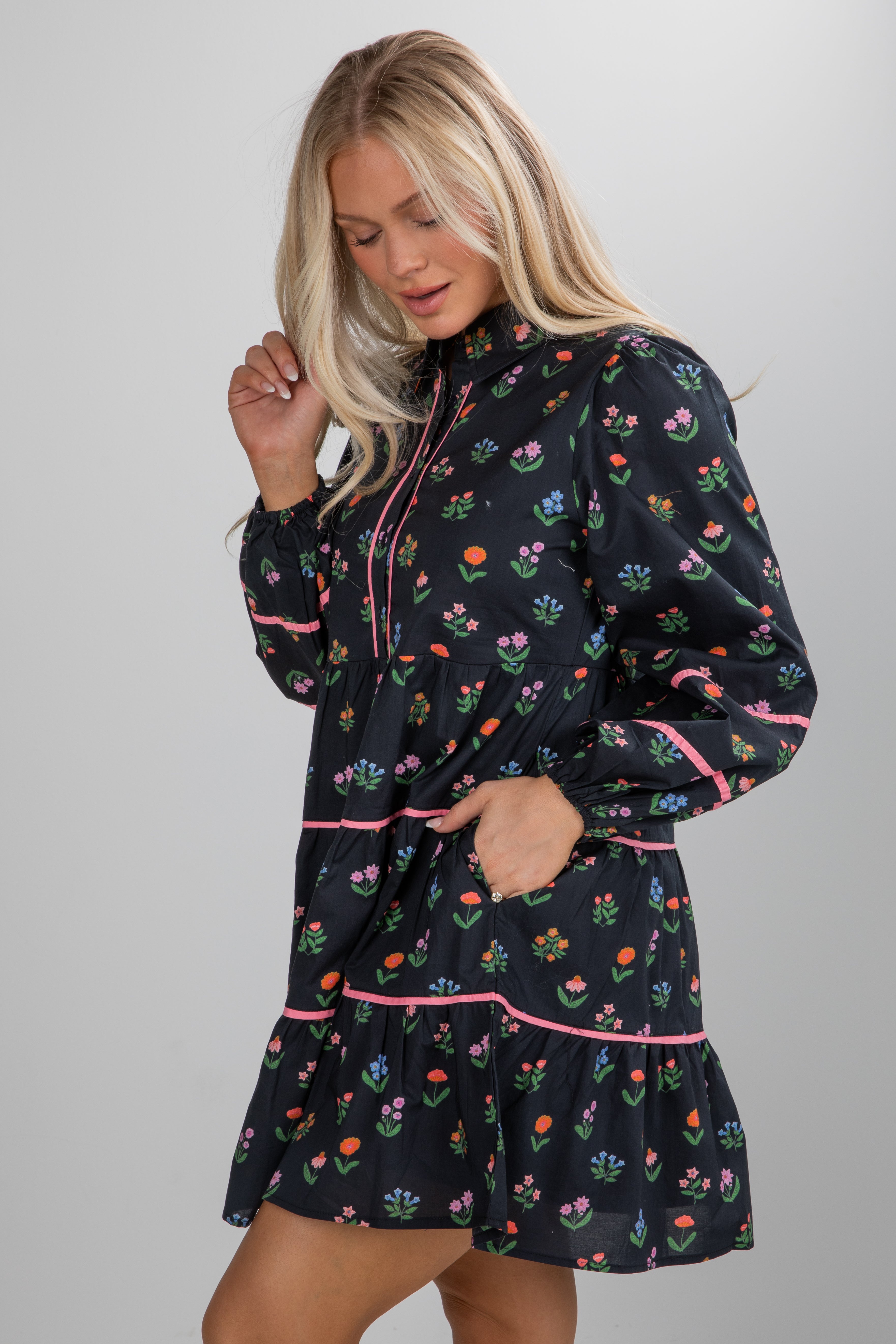 Woman wearing a black dress with colorful floral pattern on a plain background