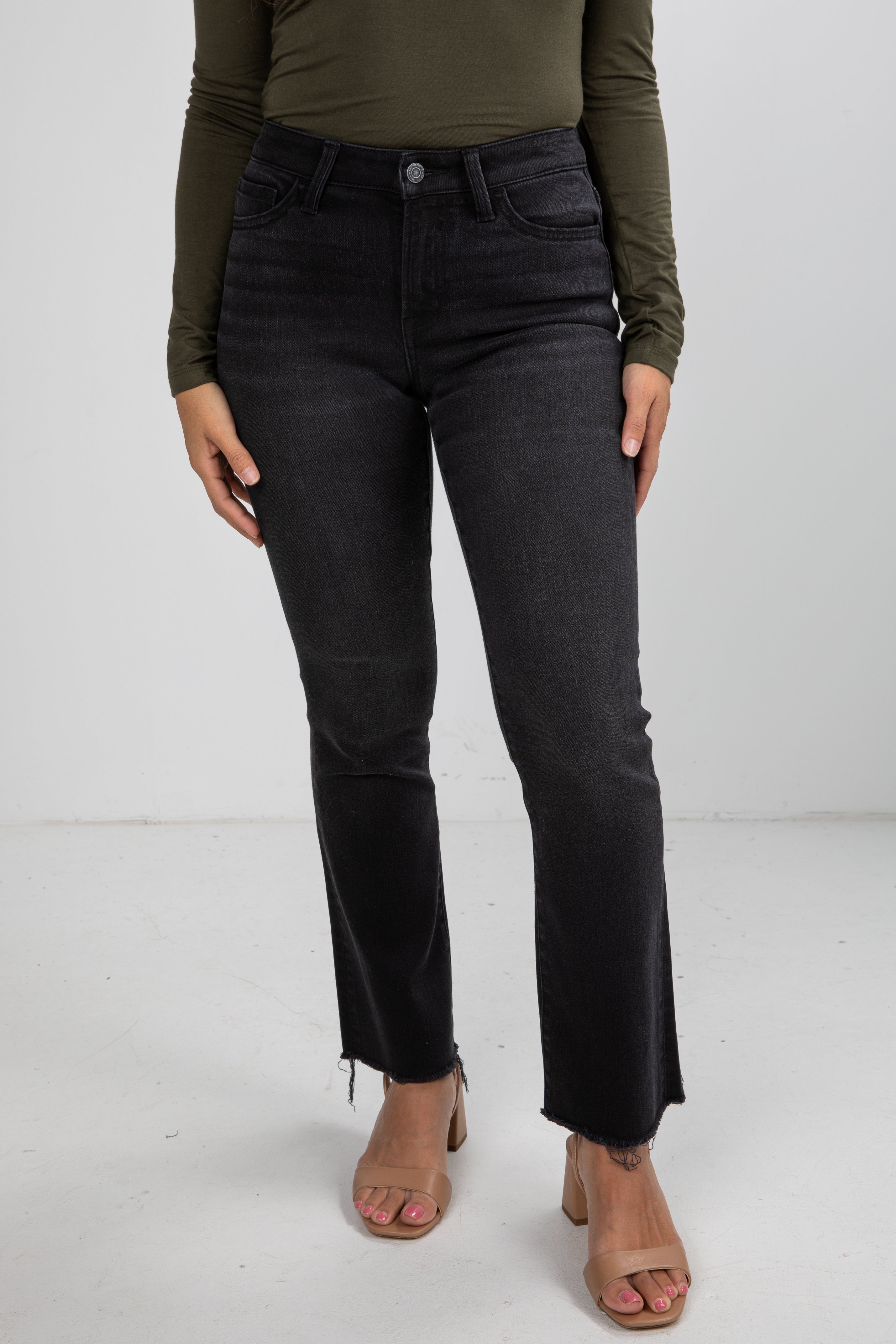 Person wearing black jeans and an olive green top on a white background