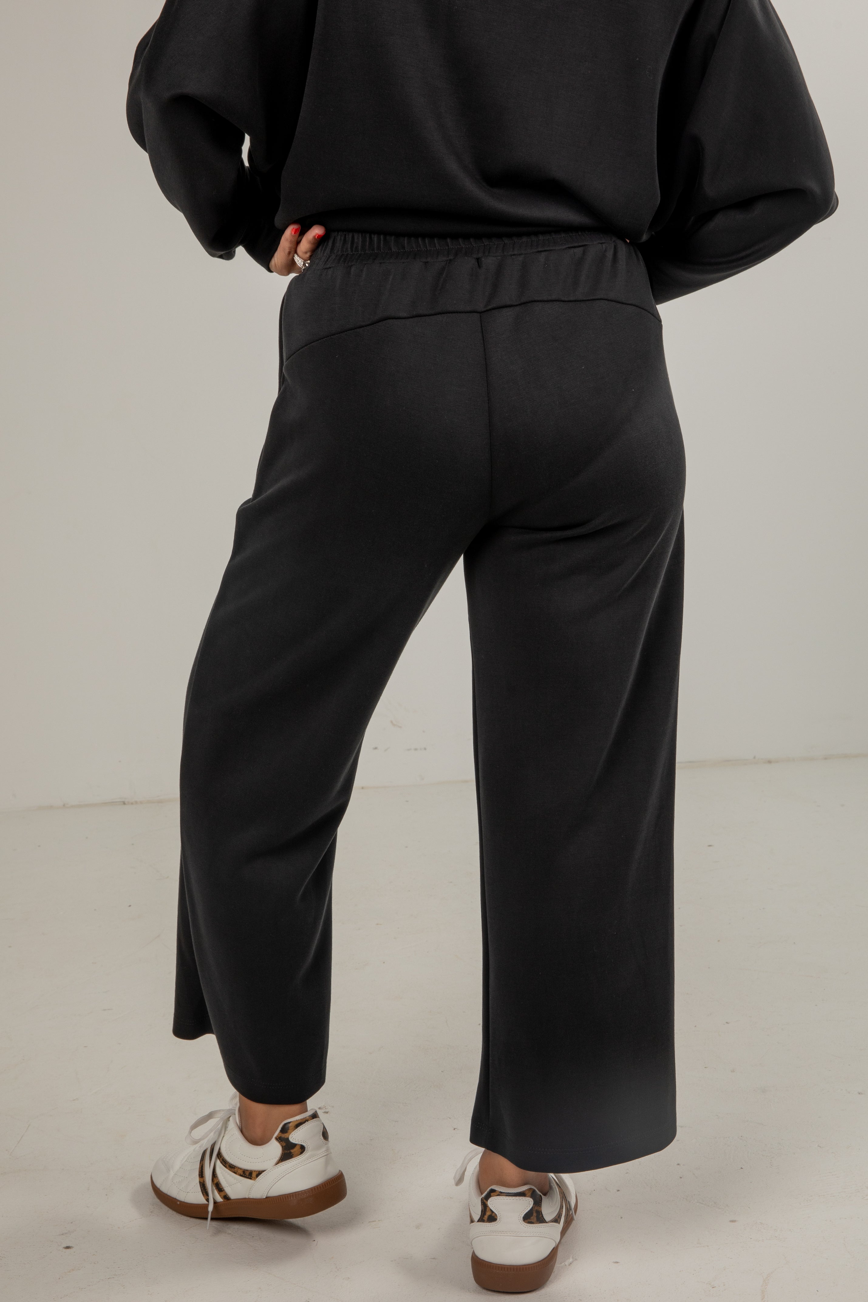 Person wearing black pants and a black top on a plain background