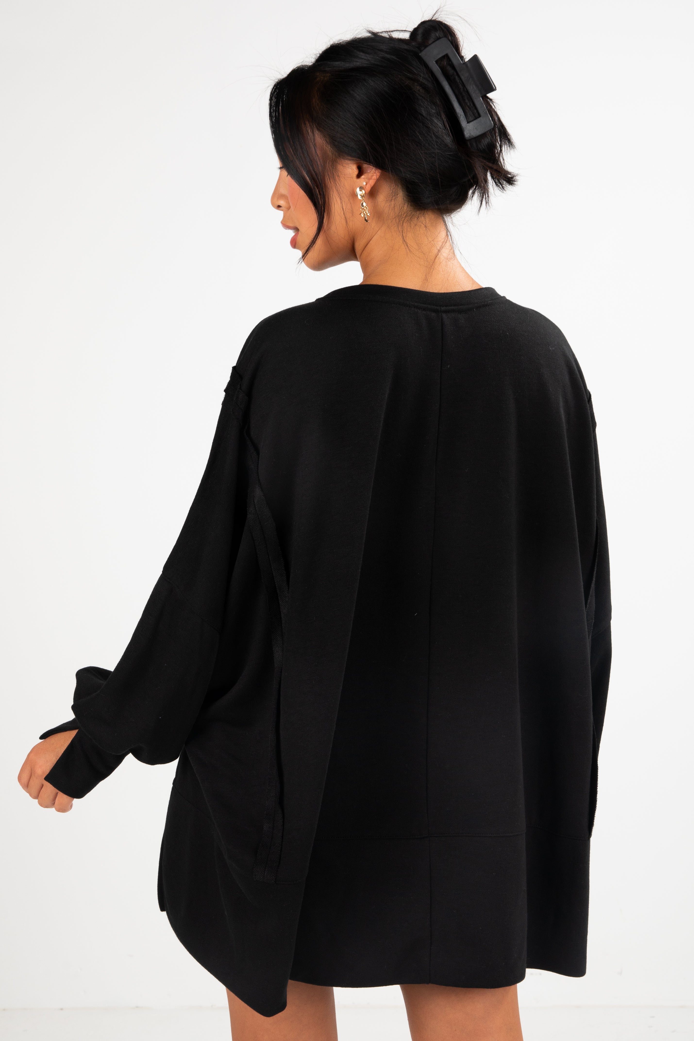 Person wearing a black oversized sweater on a white background