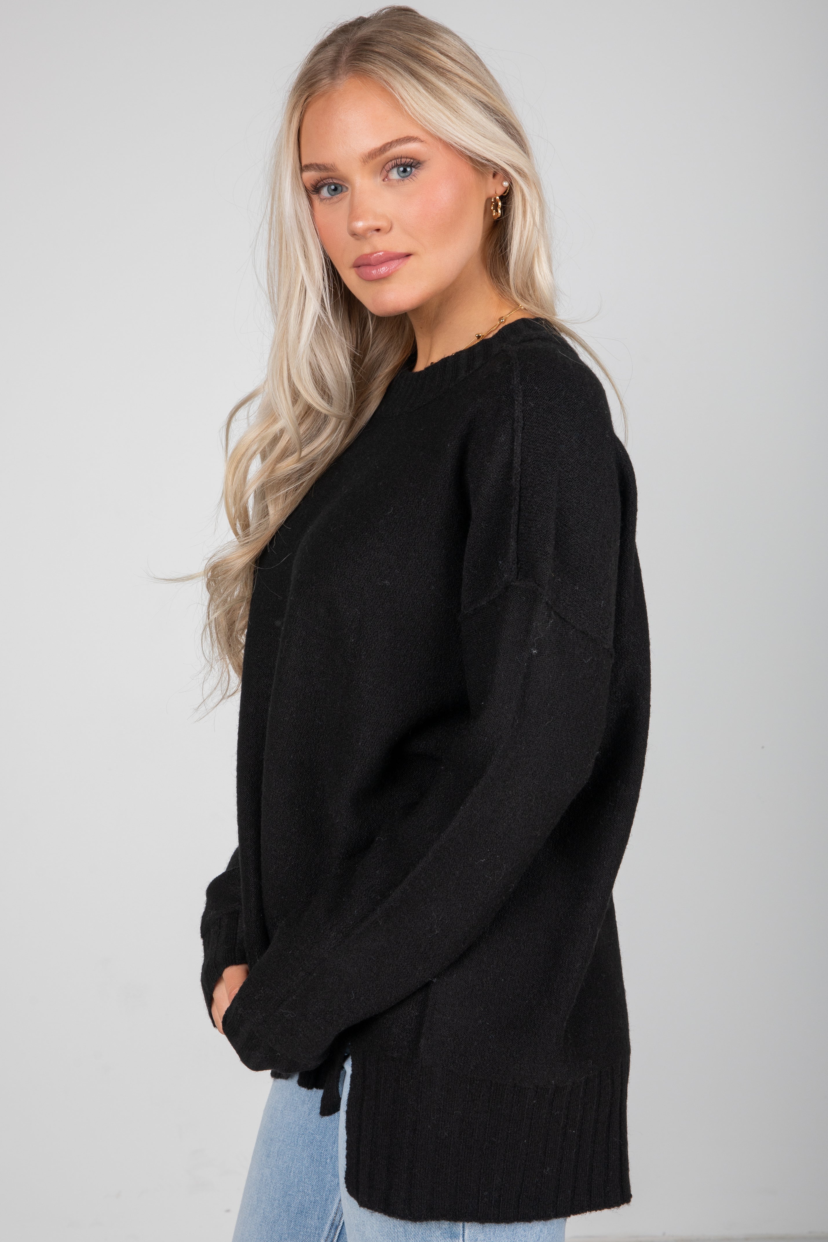 Woman wearing a black sweater against a plain background