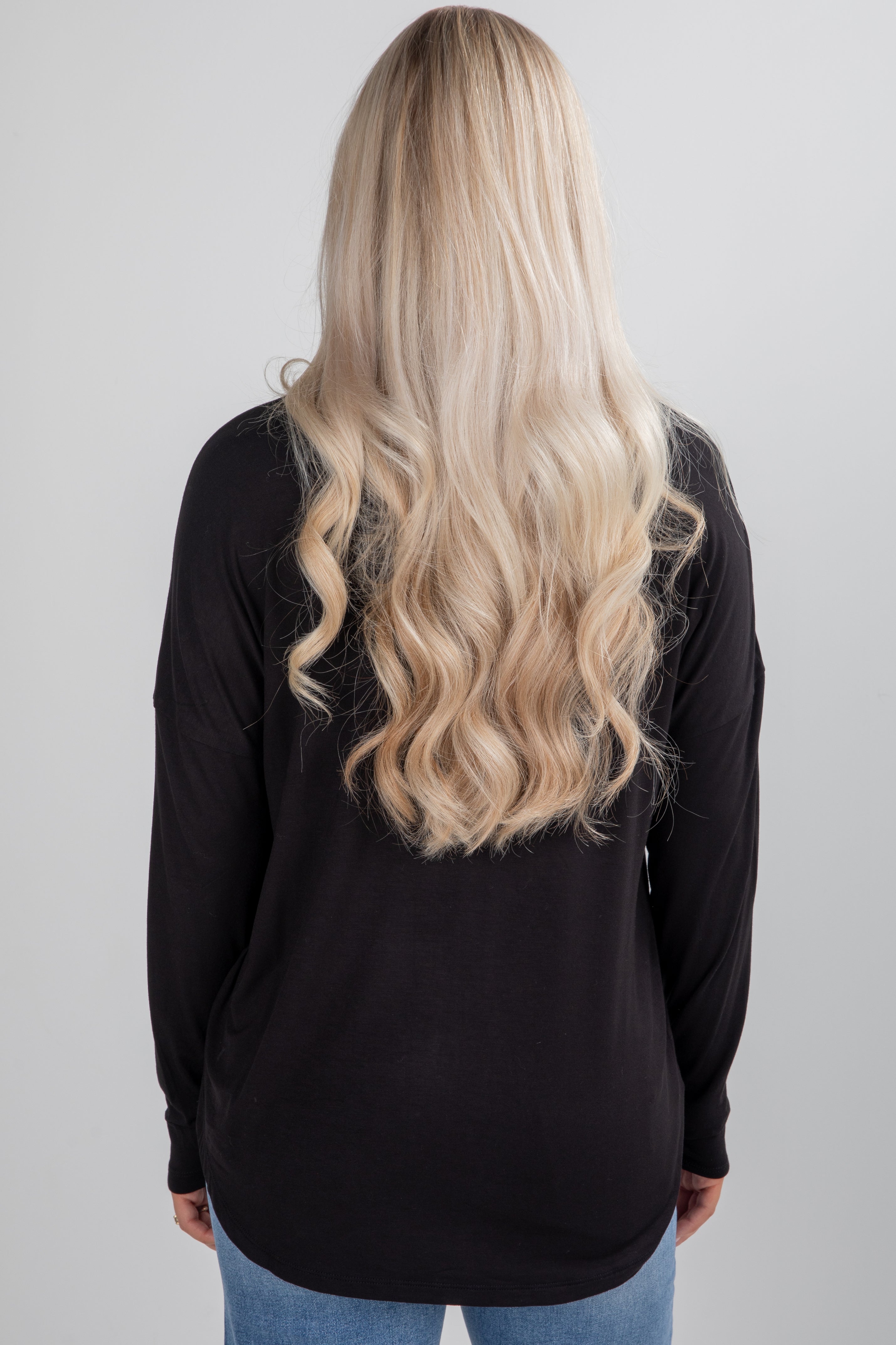 Person wearing a black long-sleeve top with a plain background