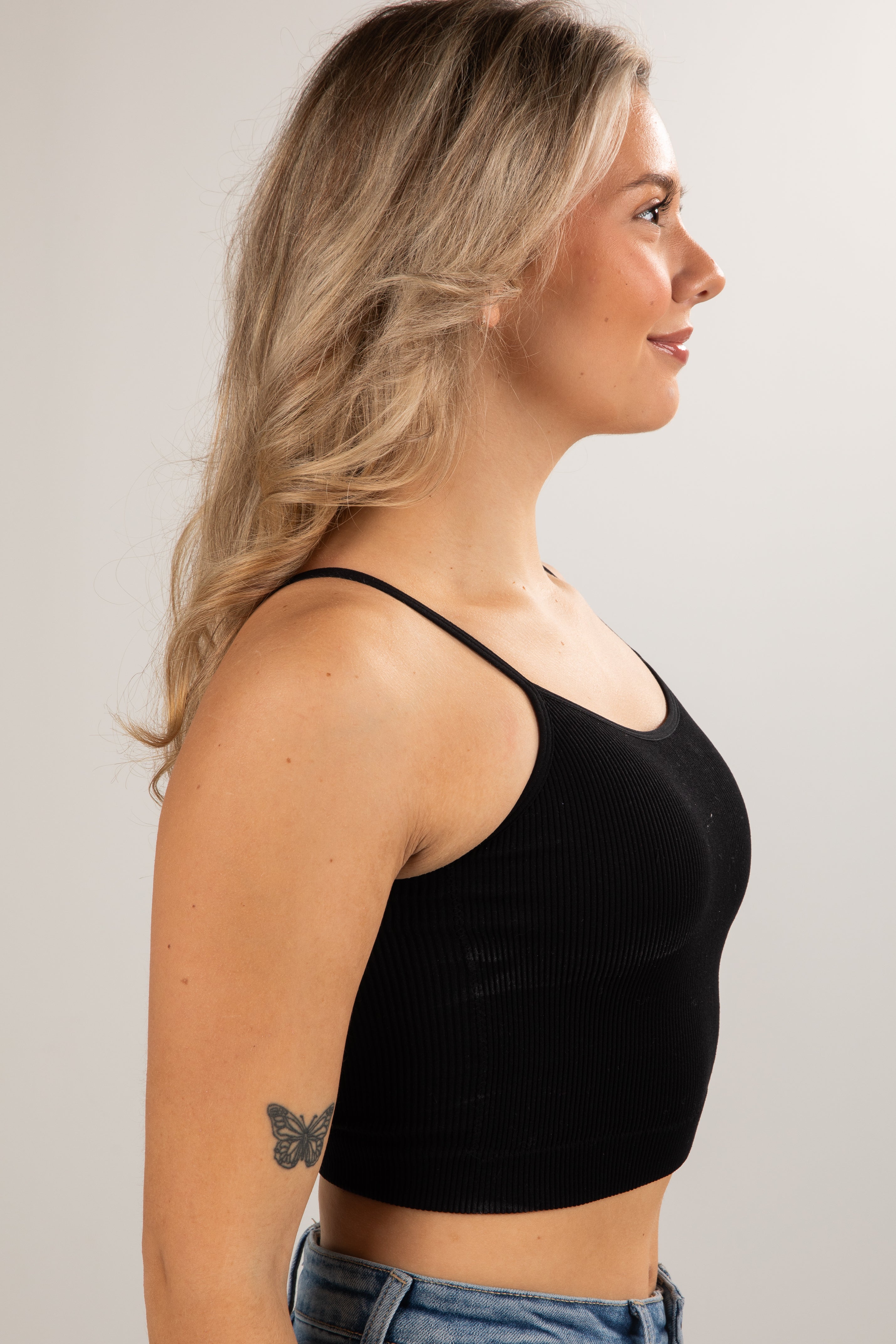 Woman wearing a black crop top against a plain background