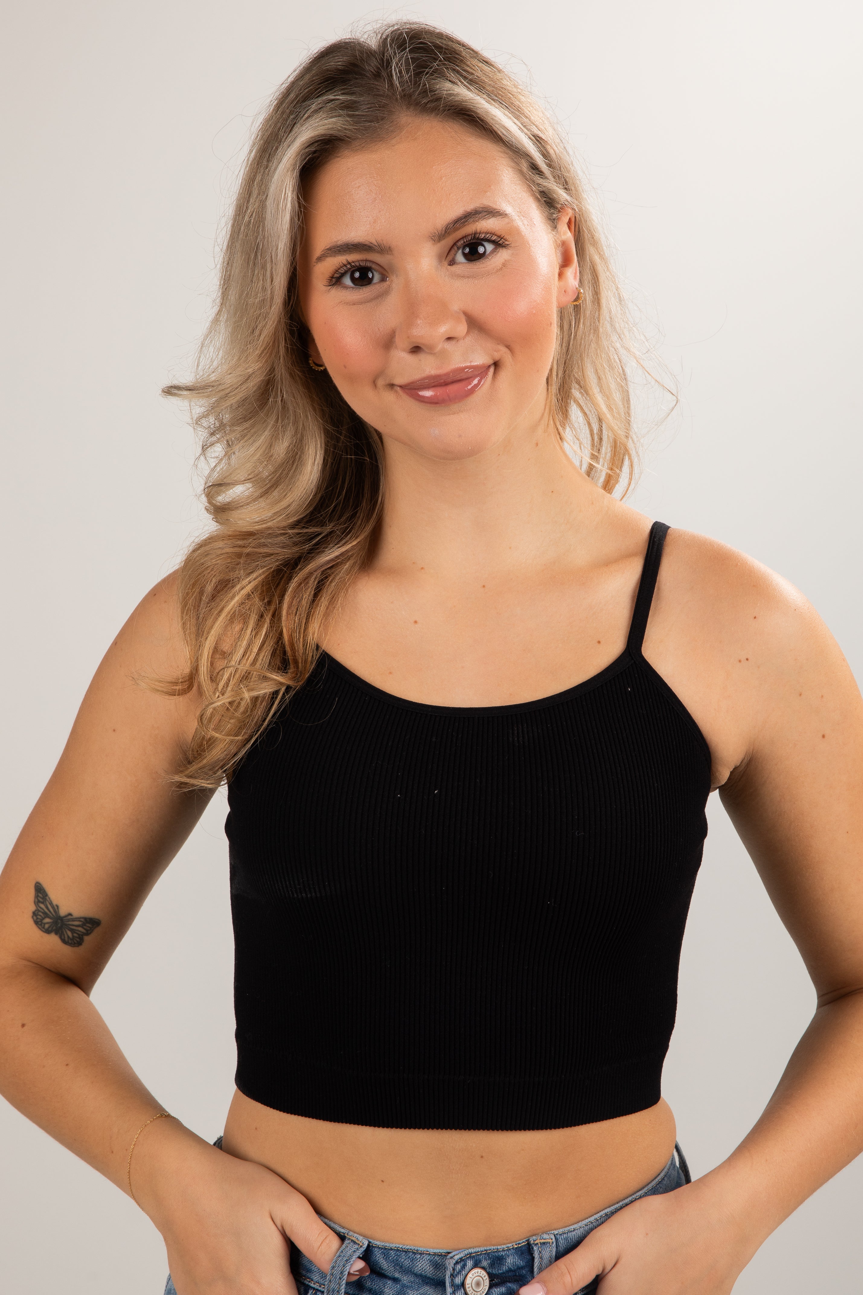 Woman wearing a black tank top against a plain background