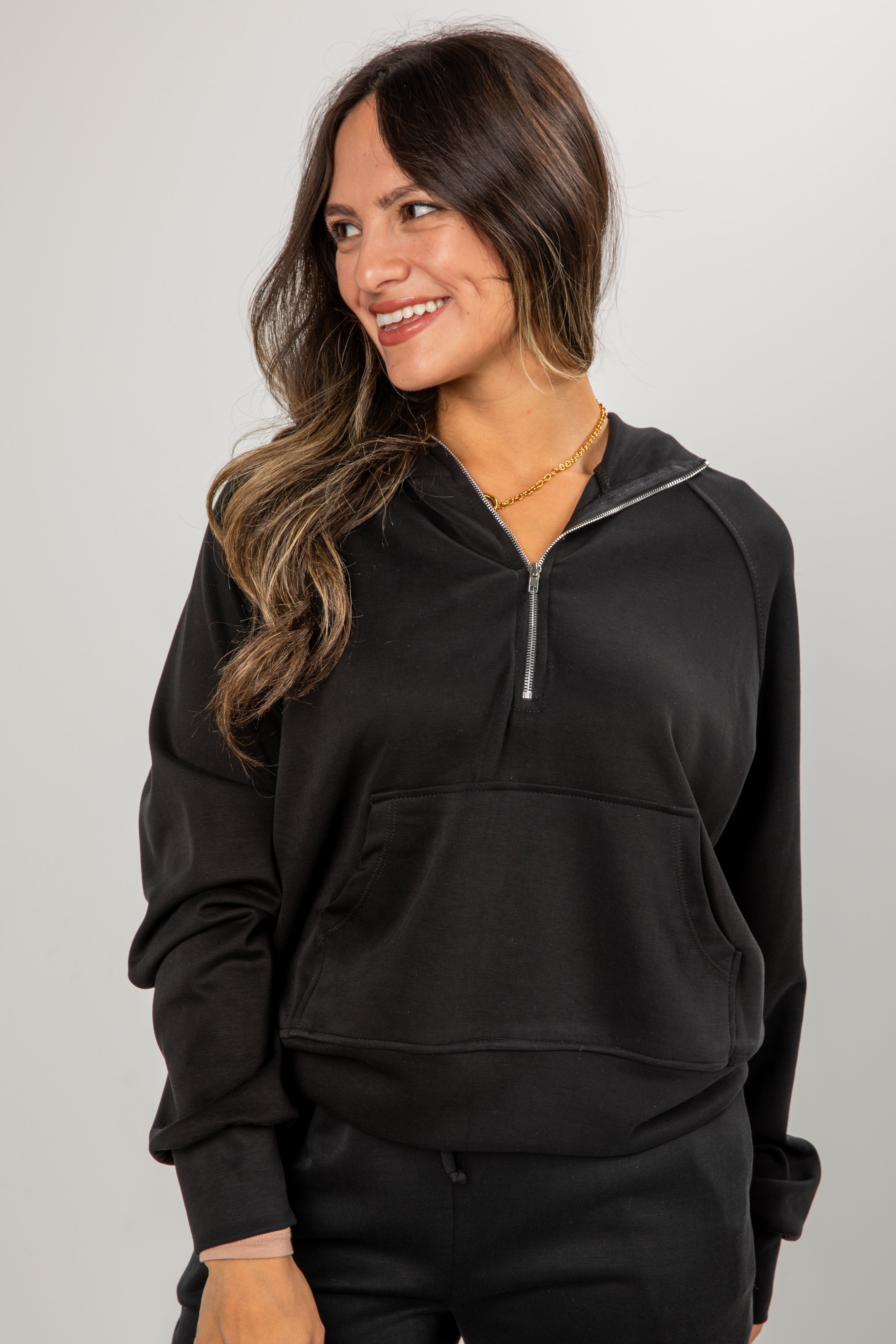Woman wearing a black half-zip sweatshirt on a plain background