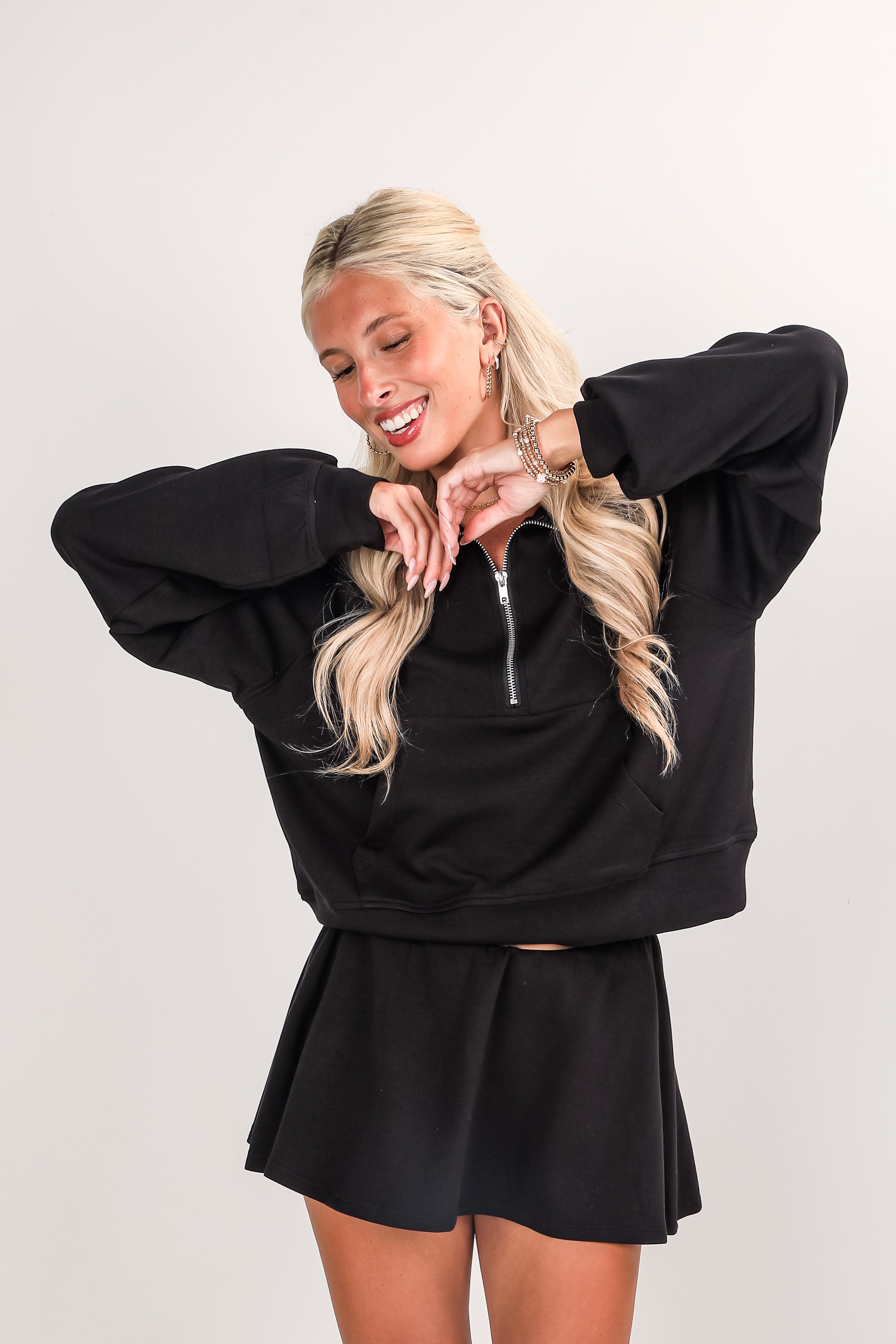 Woman wearing a black hoodie and shorts set on a plain background