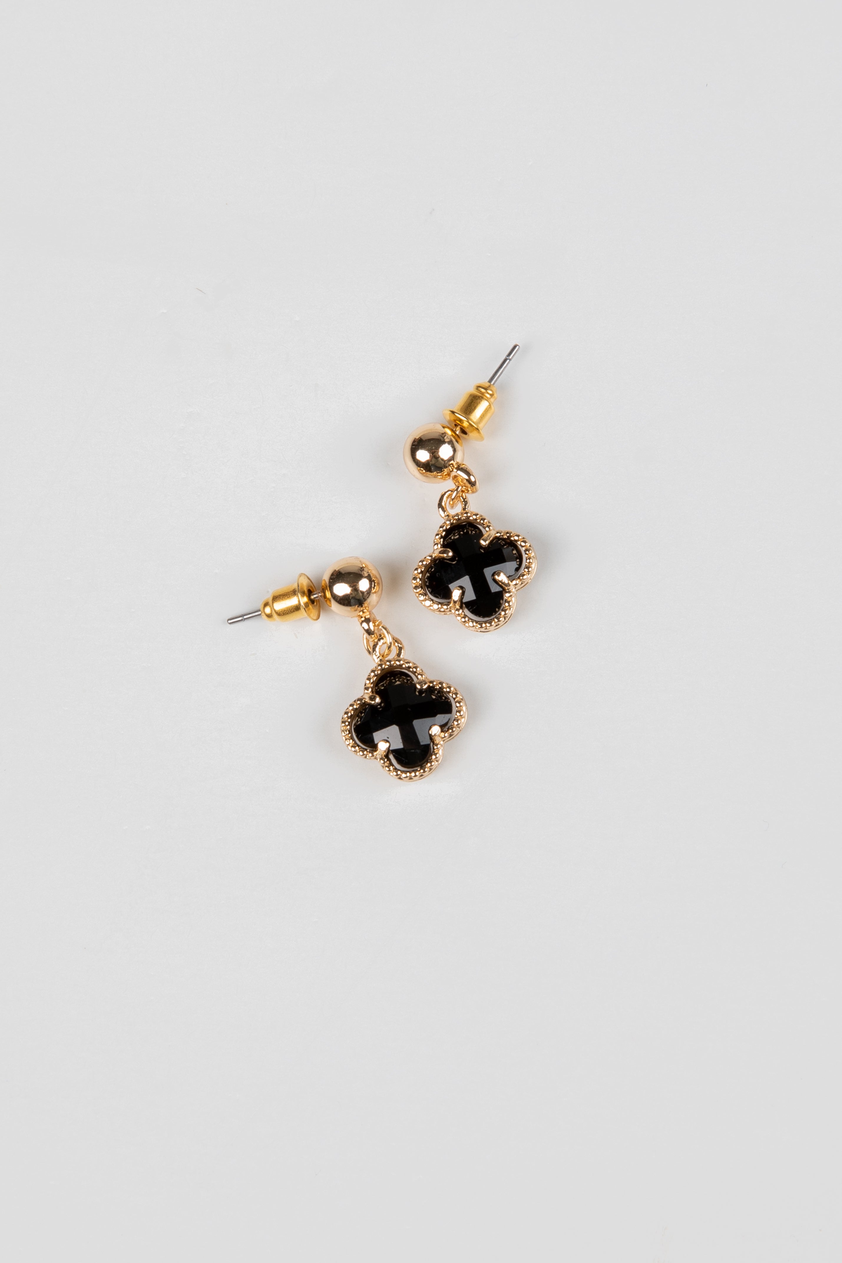 Pair of earrings with black clover-shaped drops on a light gray background