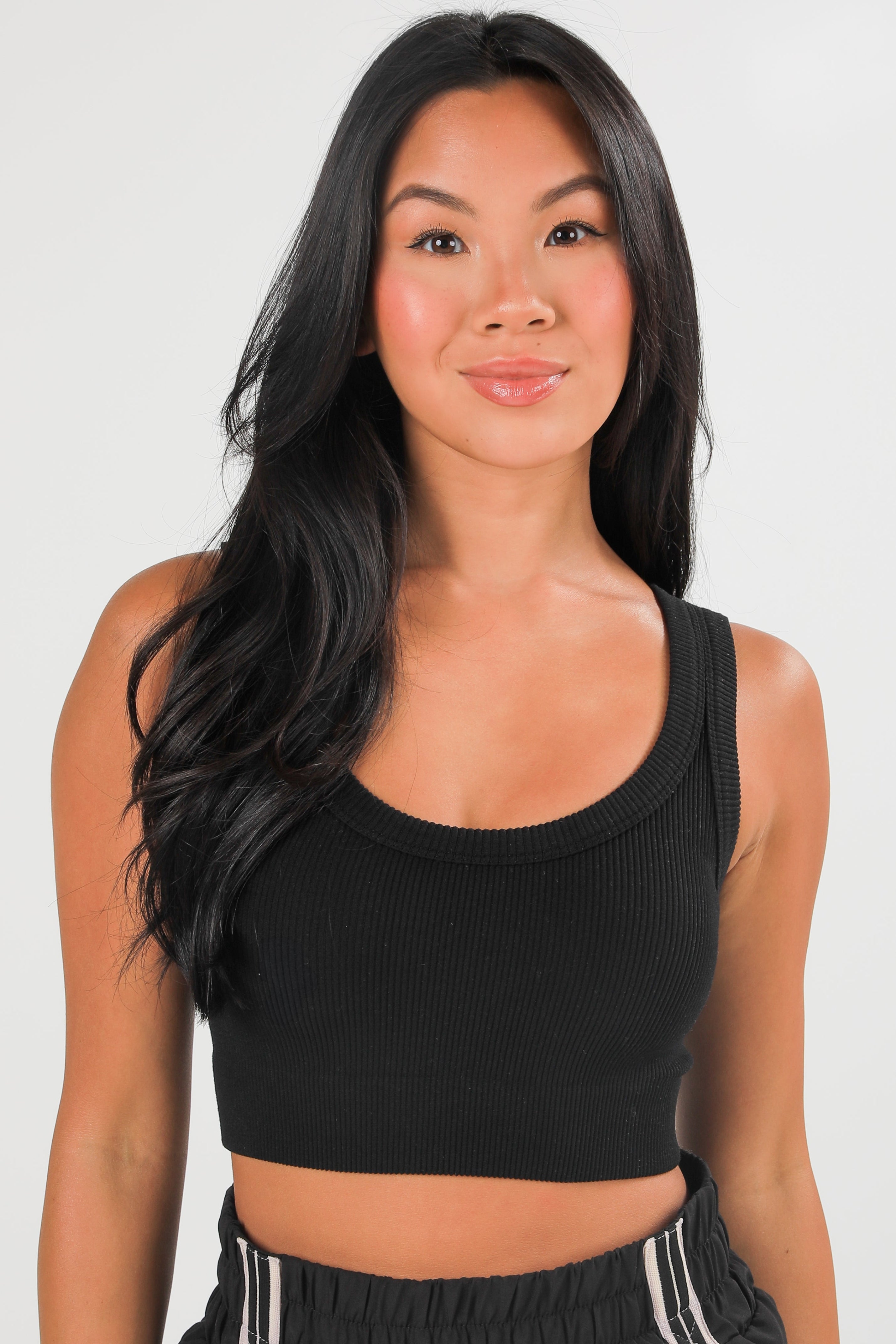 Woman wearing a black crop top against a plain background