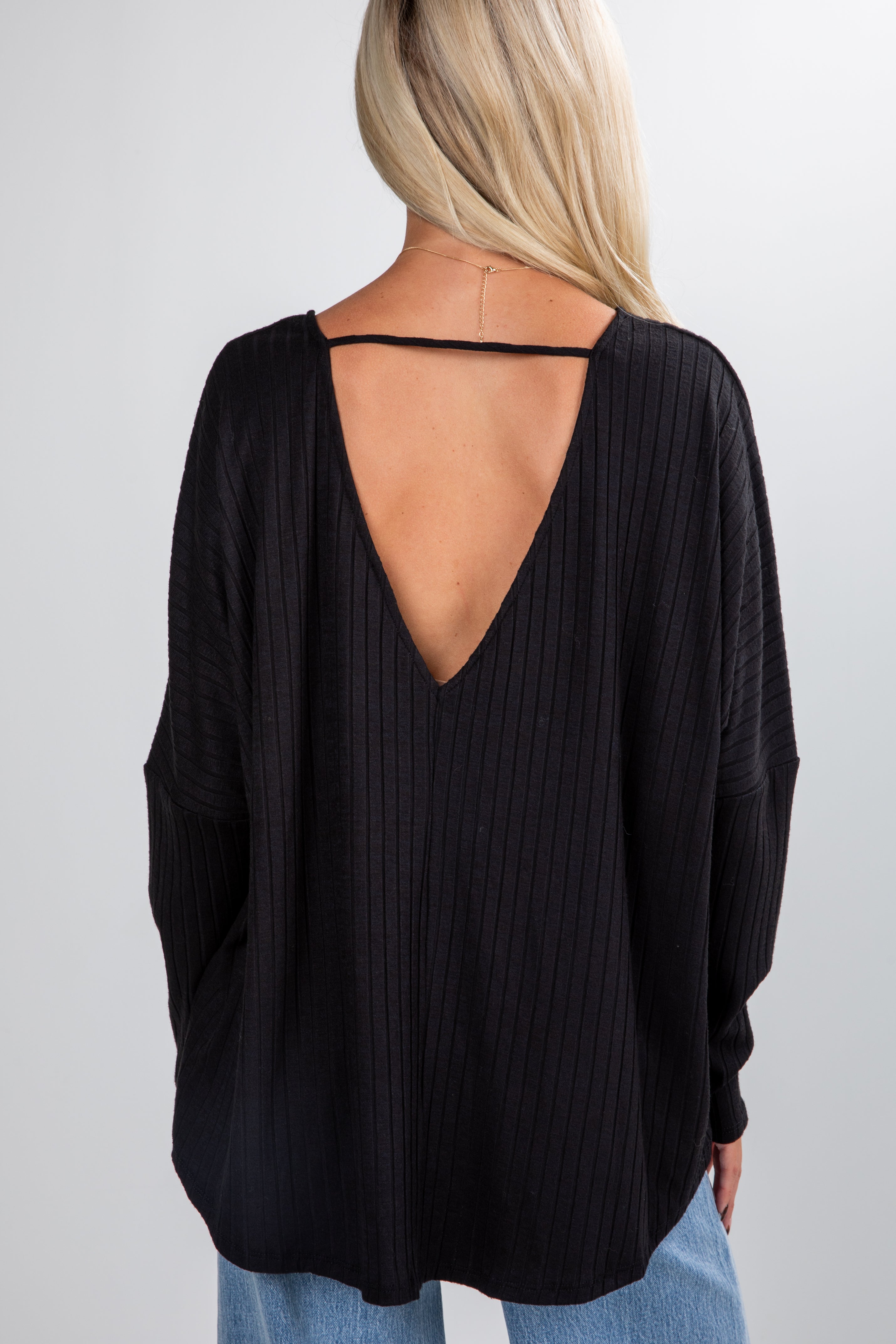Black open-back top worn by a person on a plain background