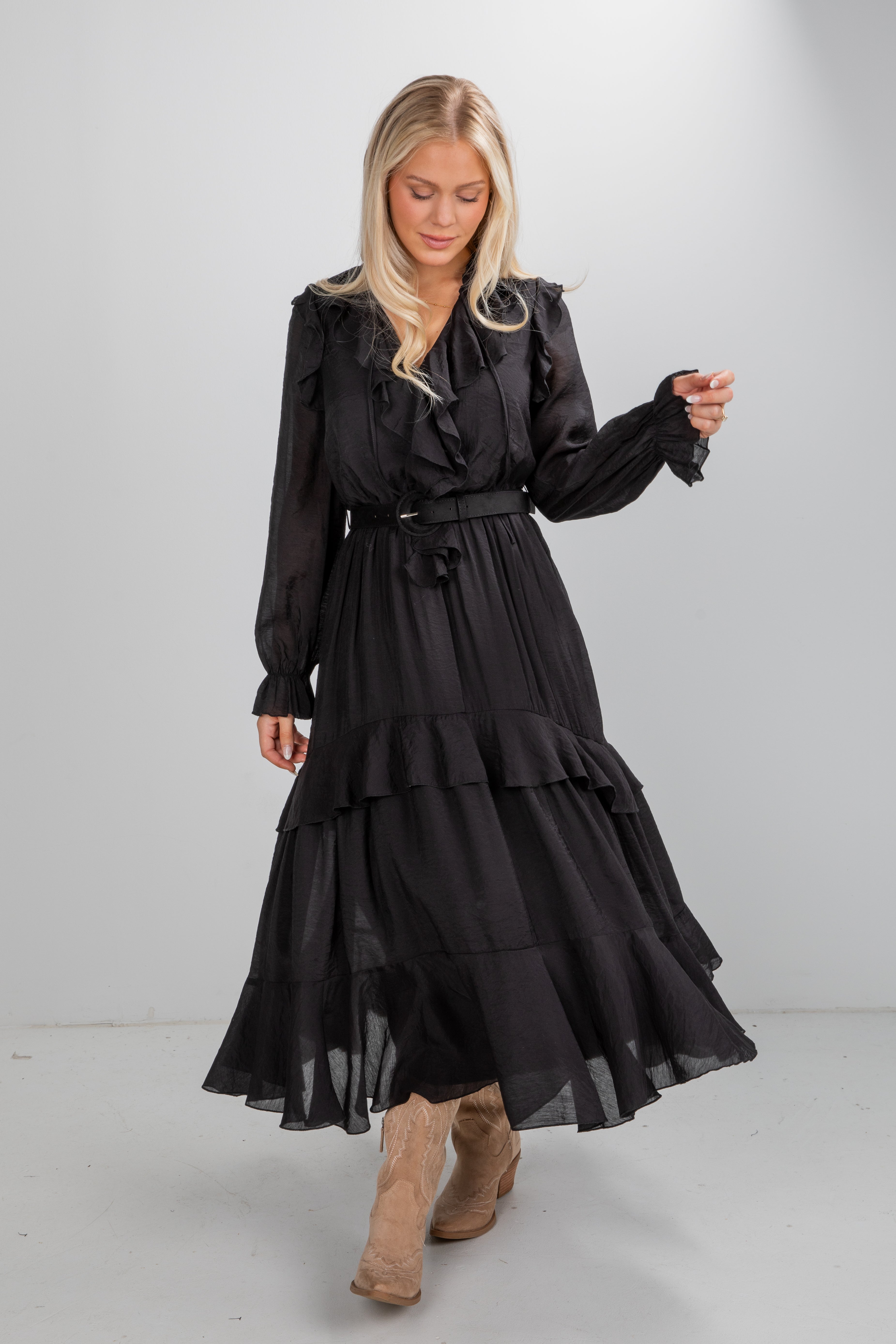 Woman wearing a black dress with long sleeves and layered skirt on a plain background