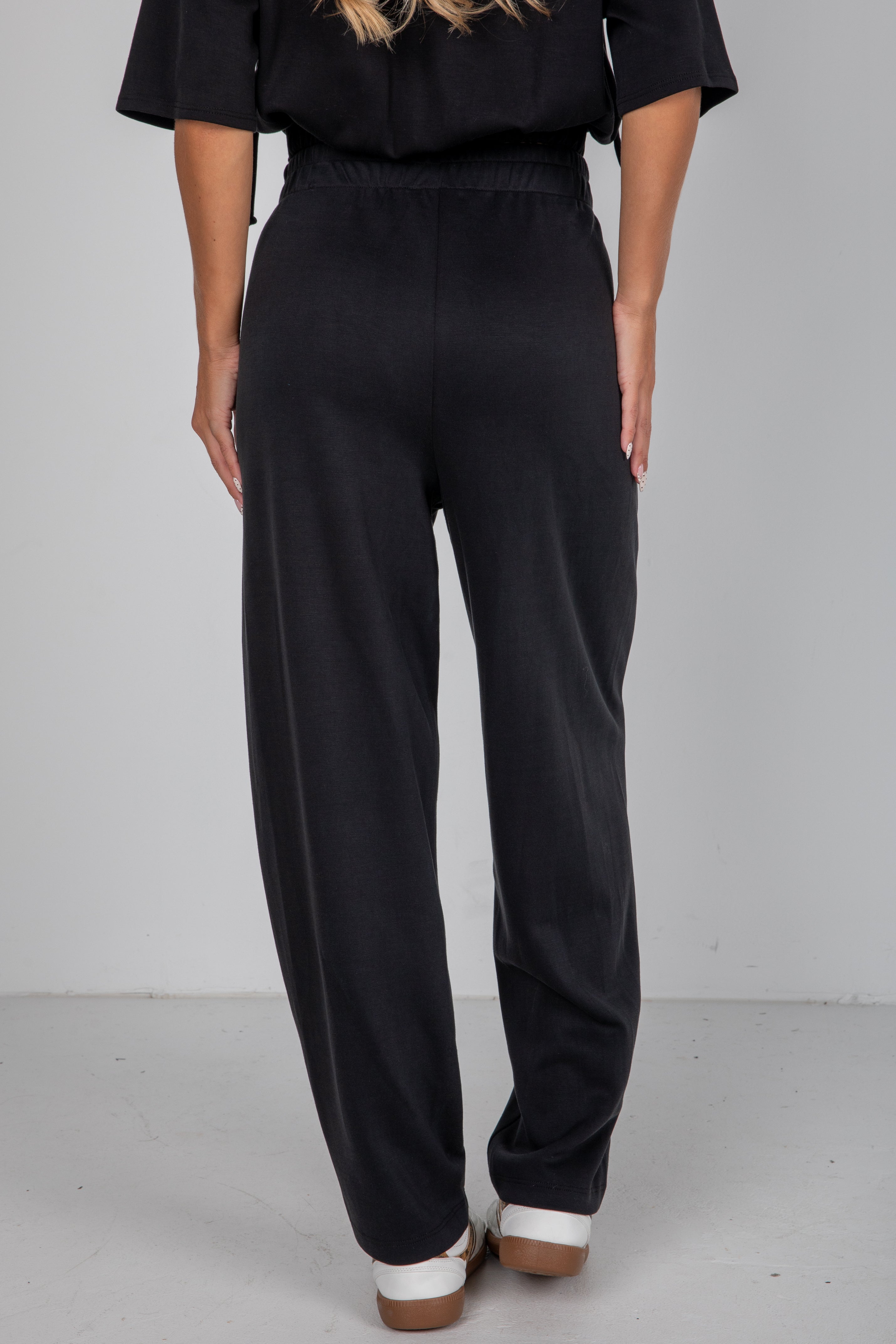 Person wearing black pants and a black top on a plain background