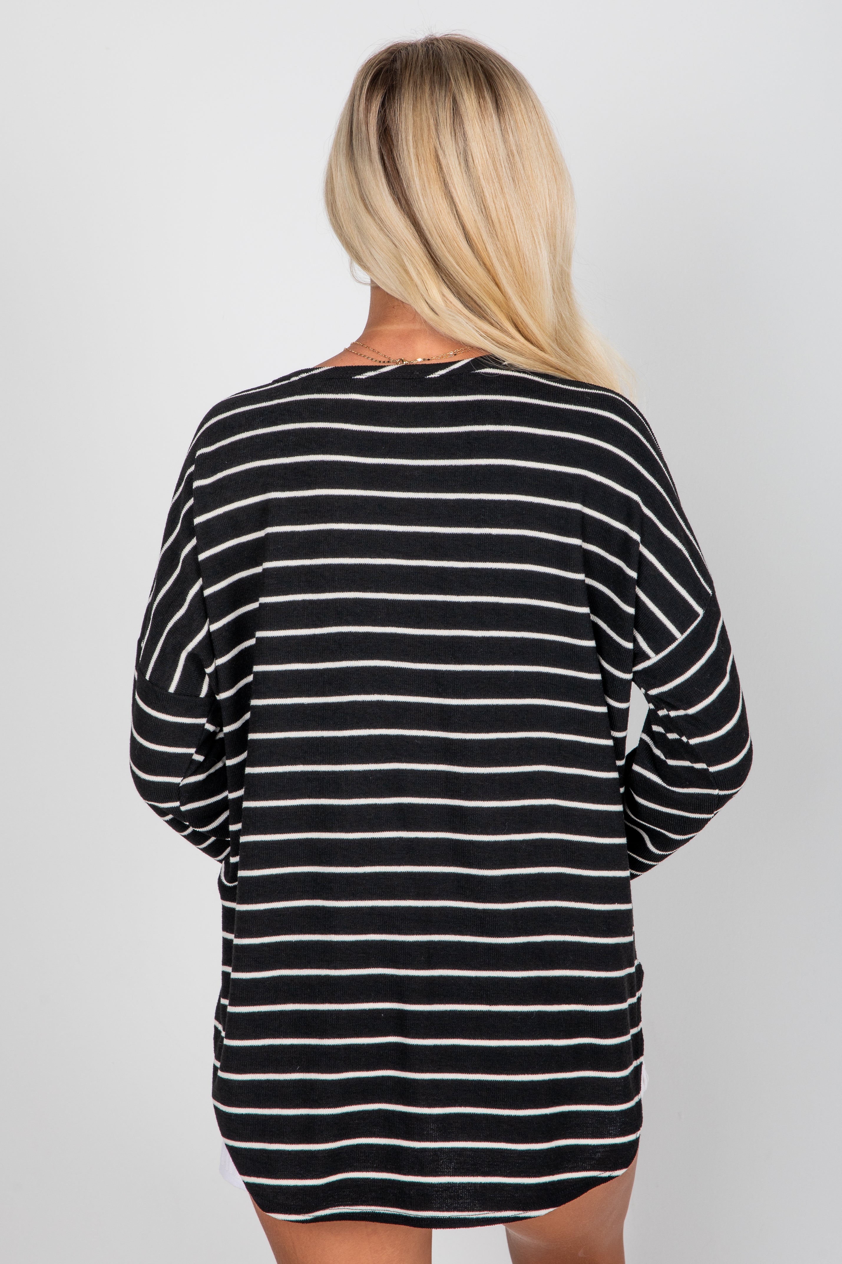 Person wearing a black and white striped long-sleeve top on a plain background