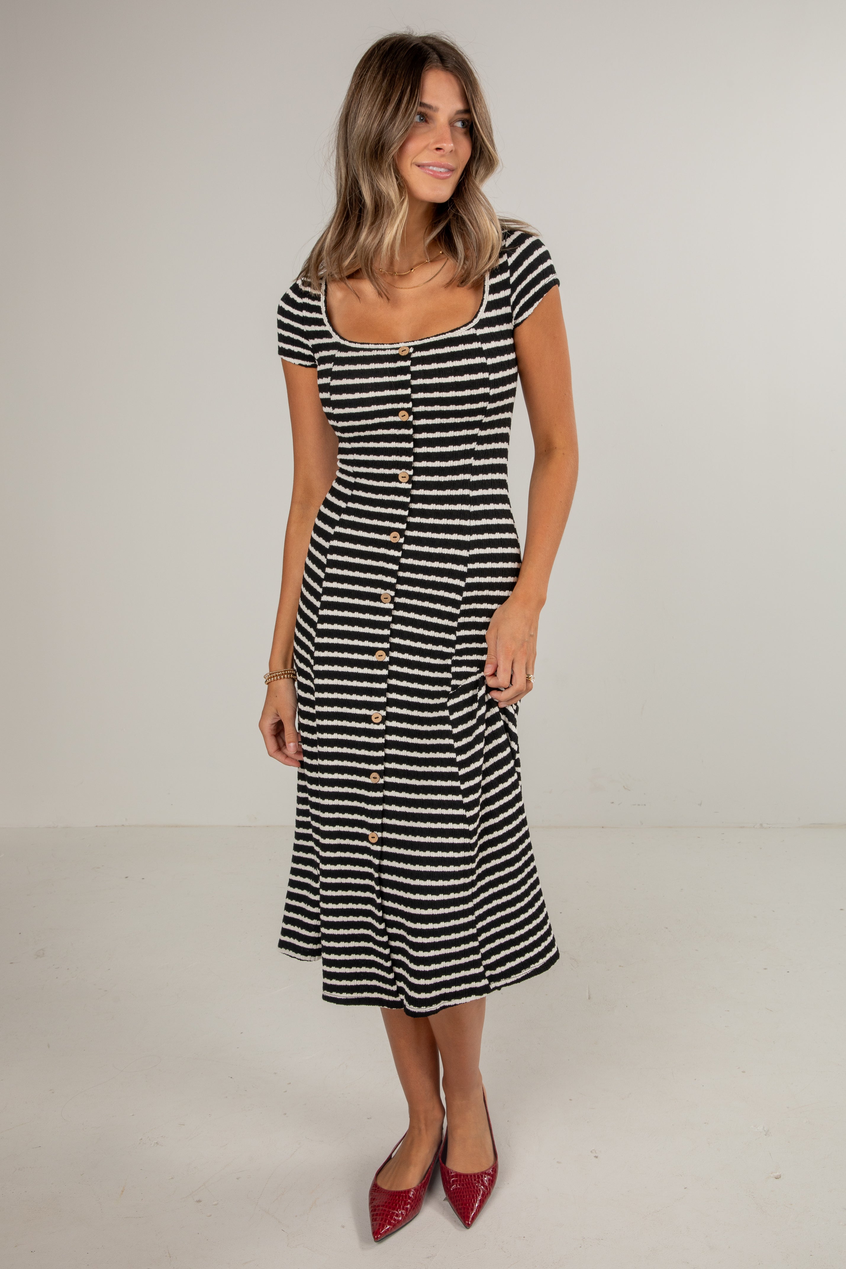 Woman wearing a black and white striped dress on a plain background