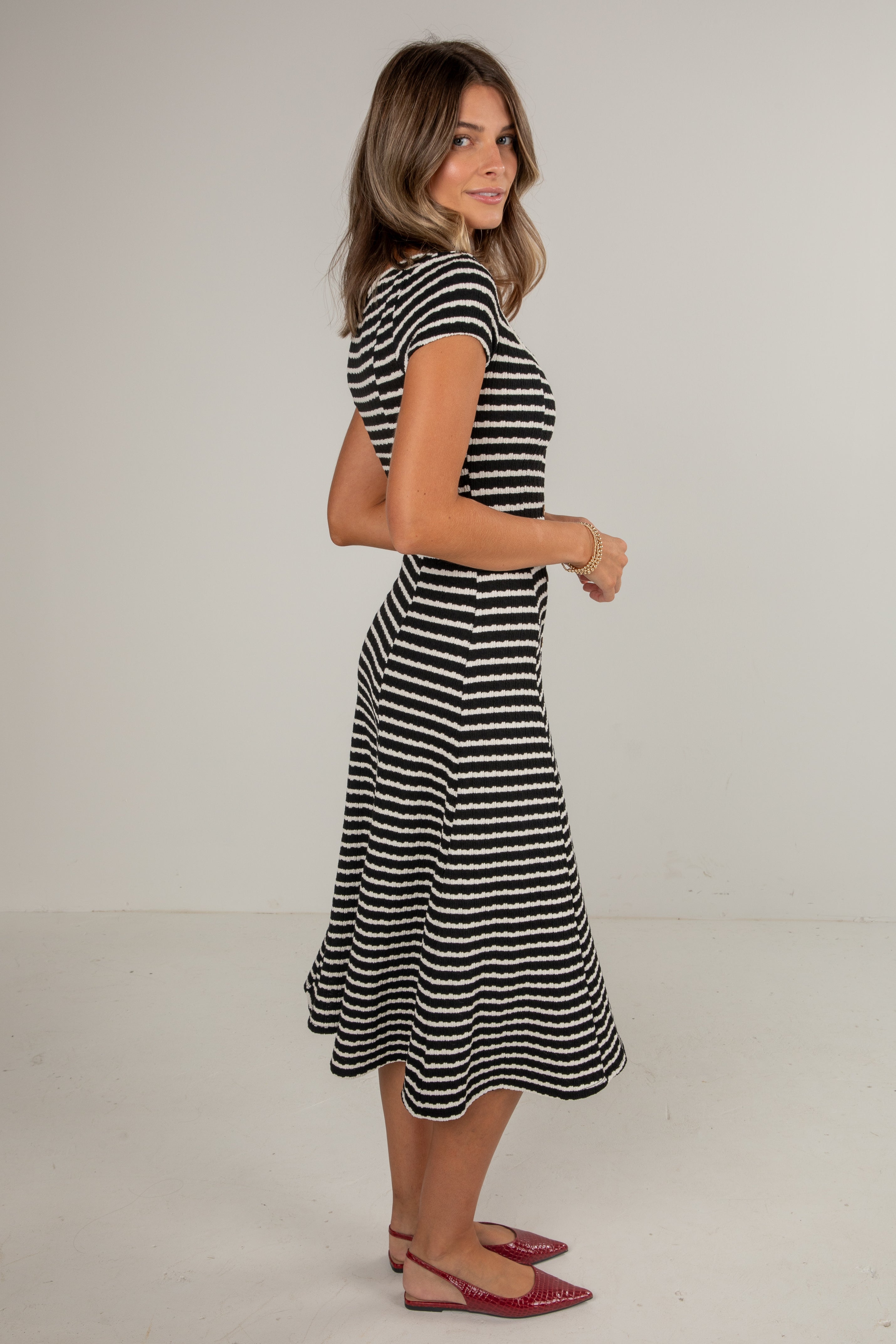 Woman wearing a black and white striped dress on a plain background