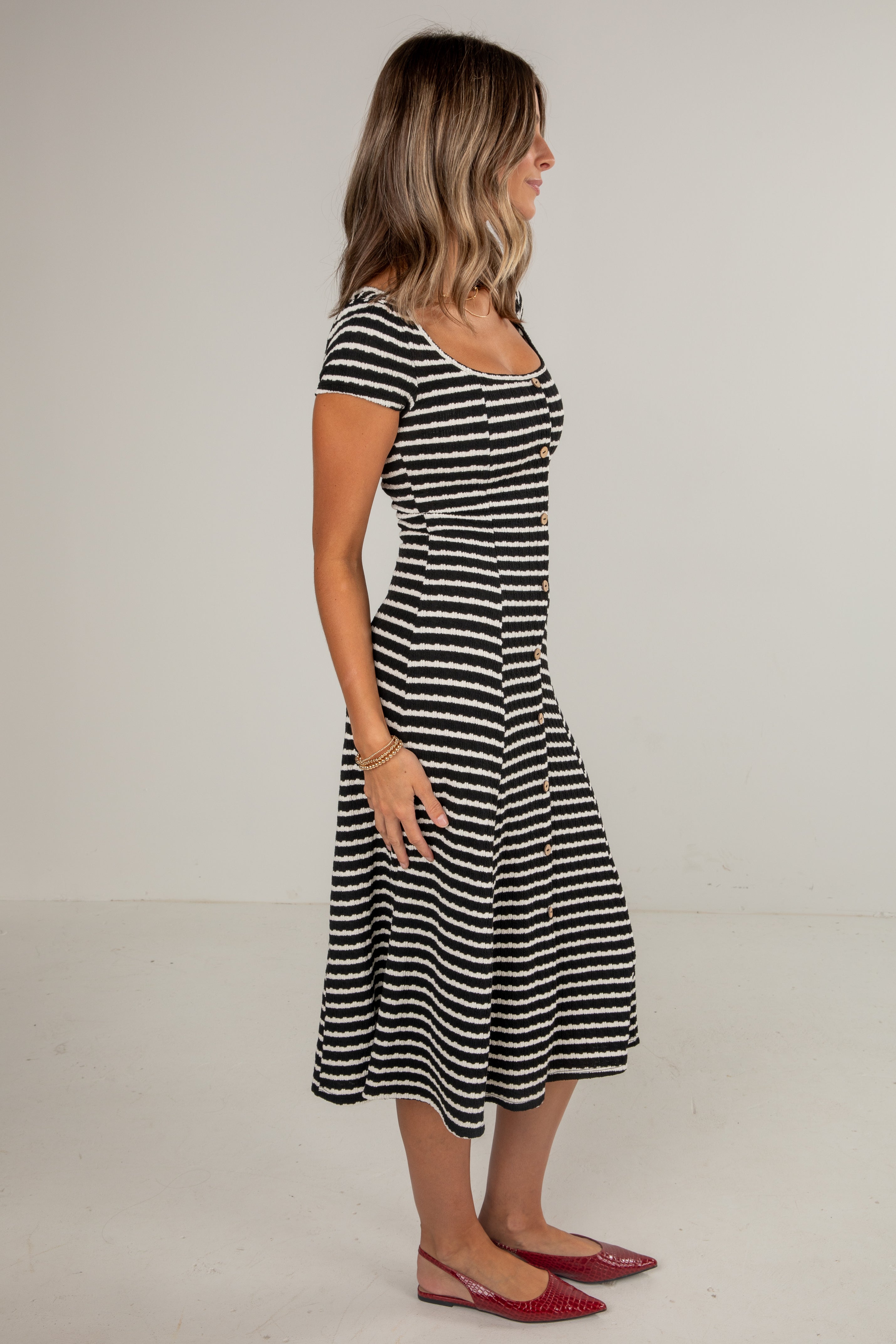 Woman wearing a black and white striped dress on a plain background