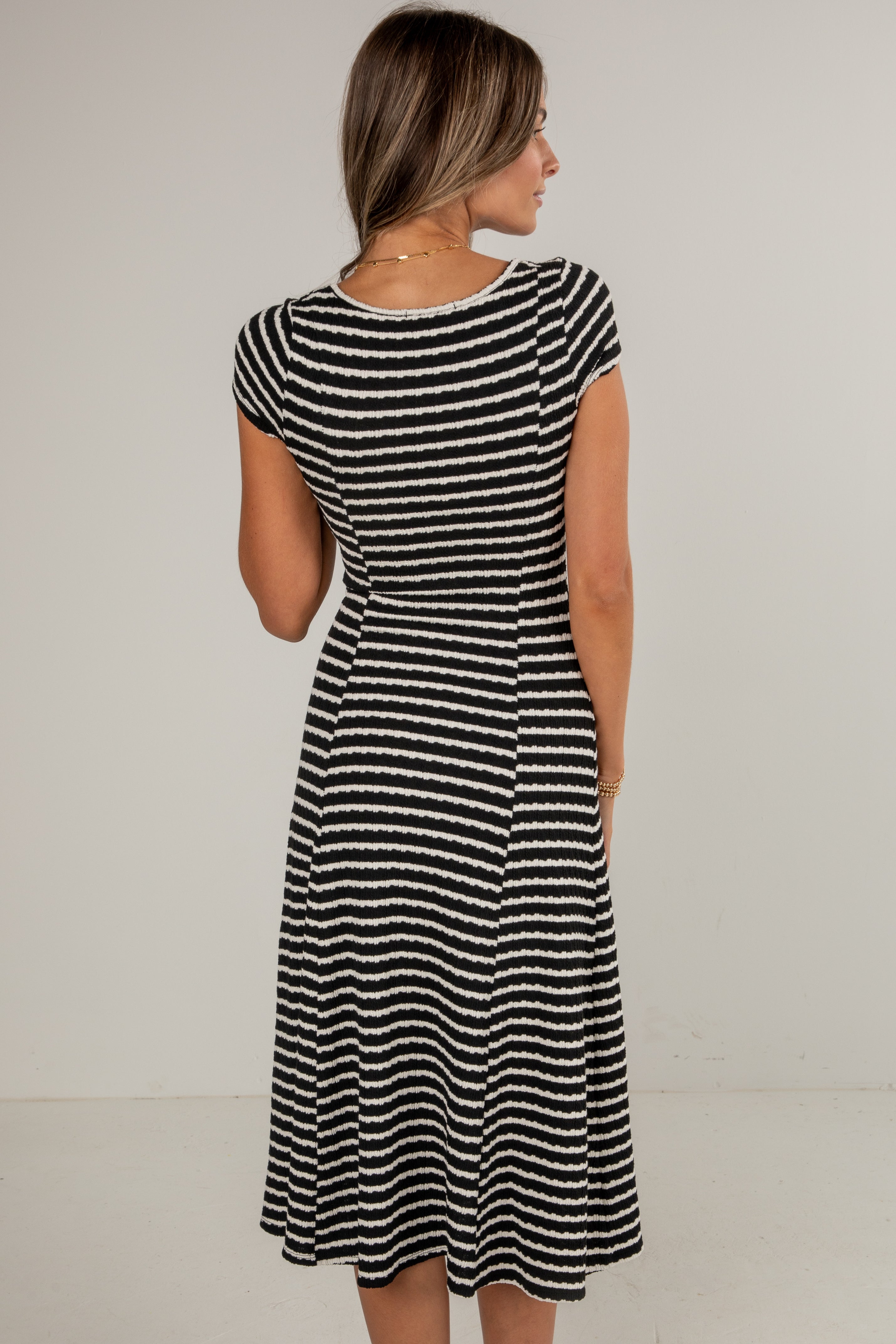 Woman wearing a black and white striped dress against a plain background