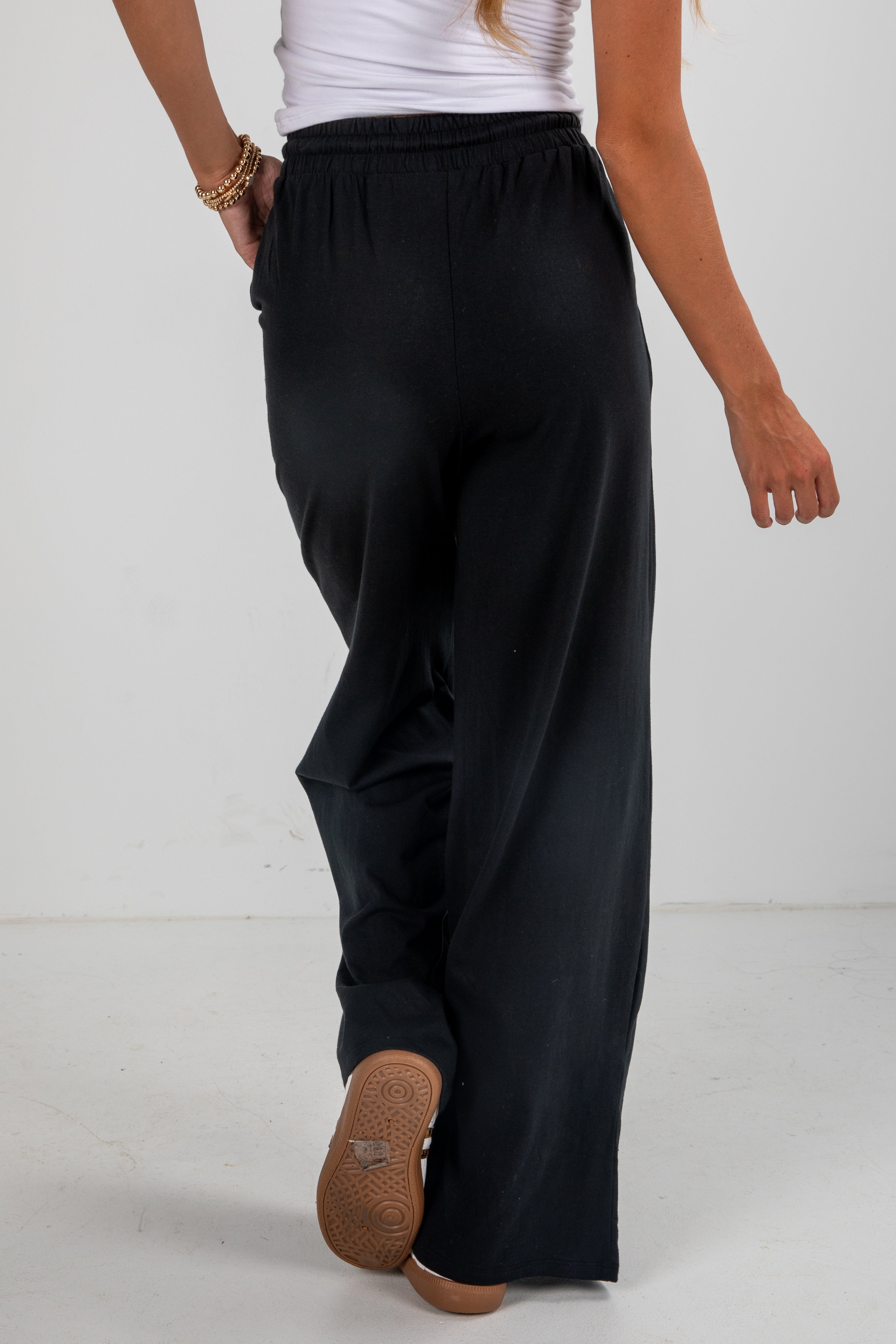 Person wearing black wide-leg pants on a white background