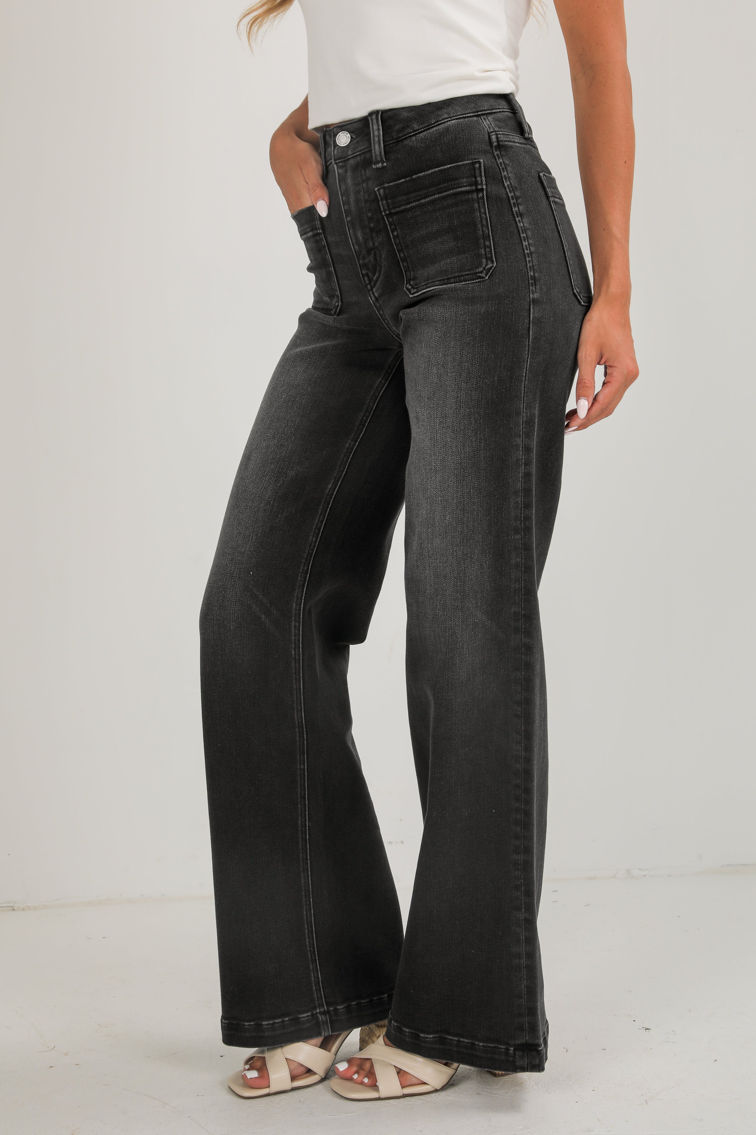 Person wearing black flared jeans on a white background