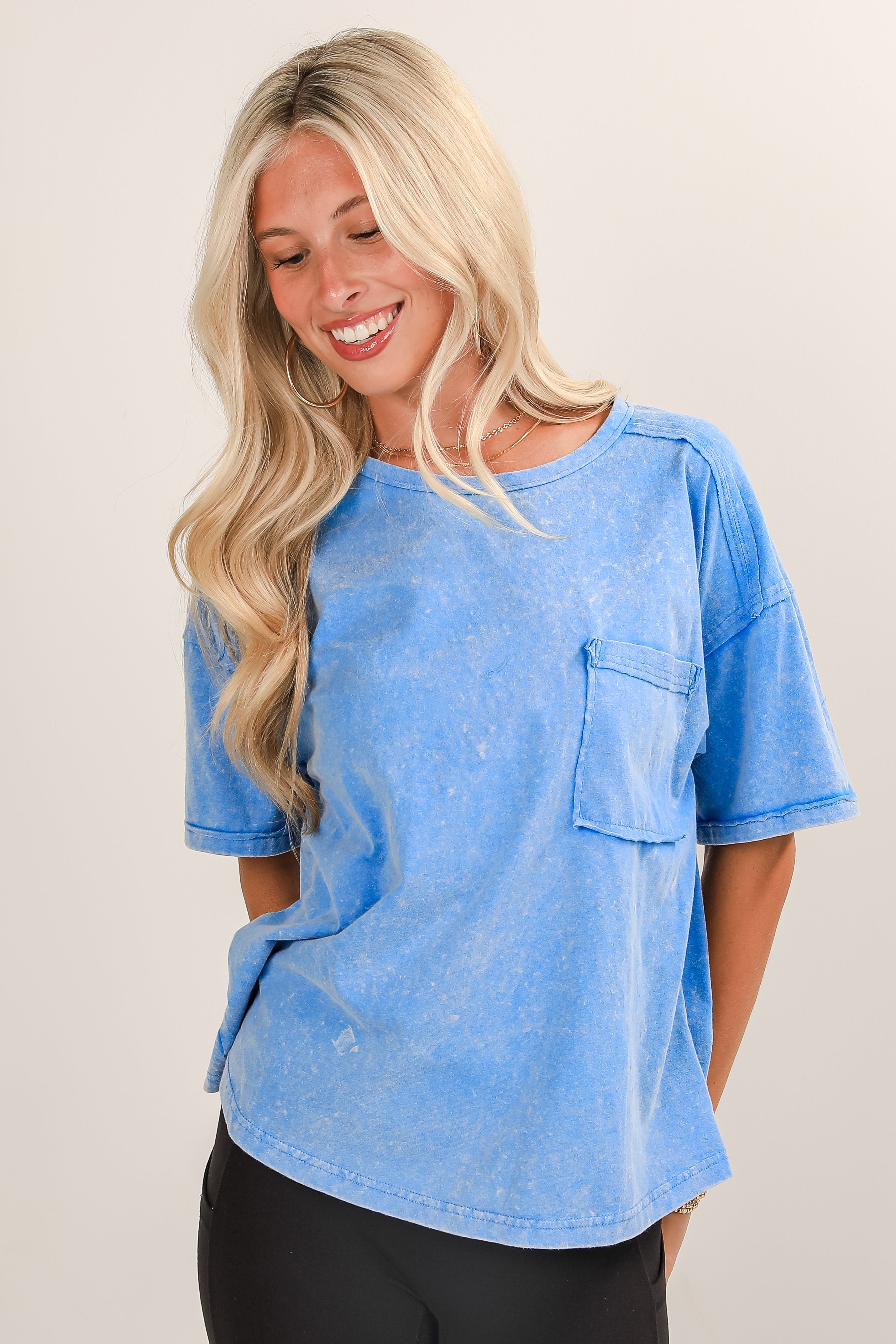 Woman wearing a blue t-shirt with a pocket on a plain background