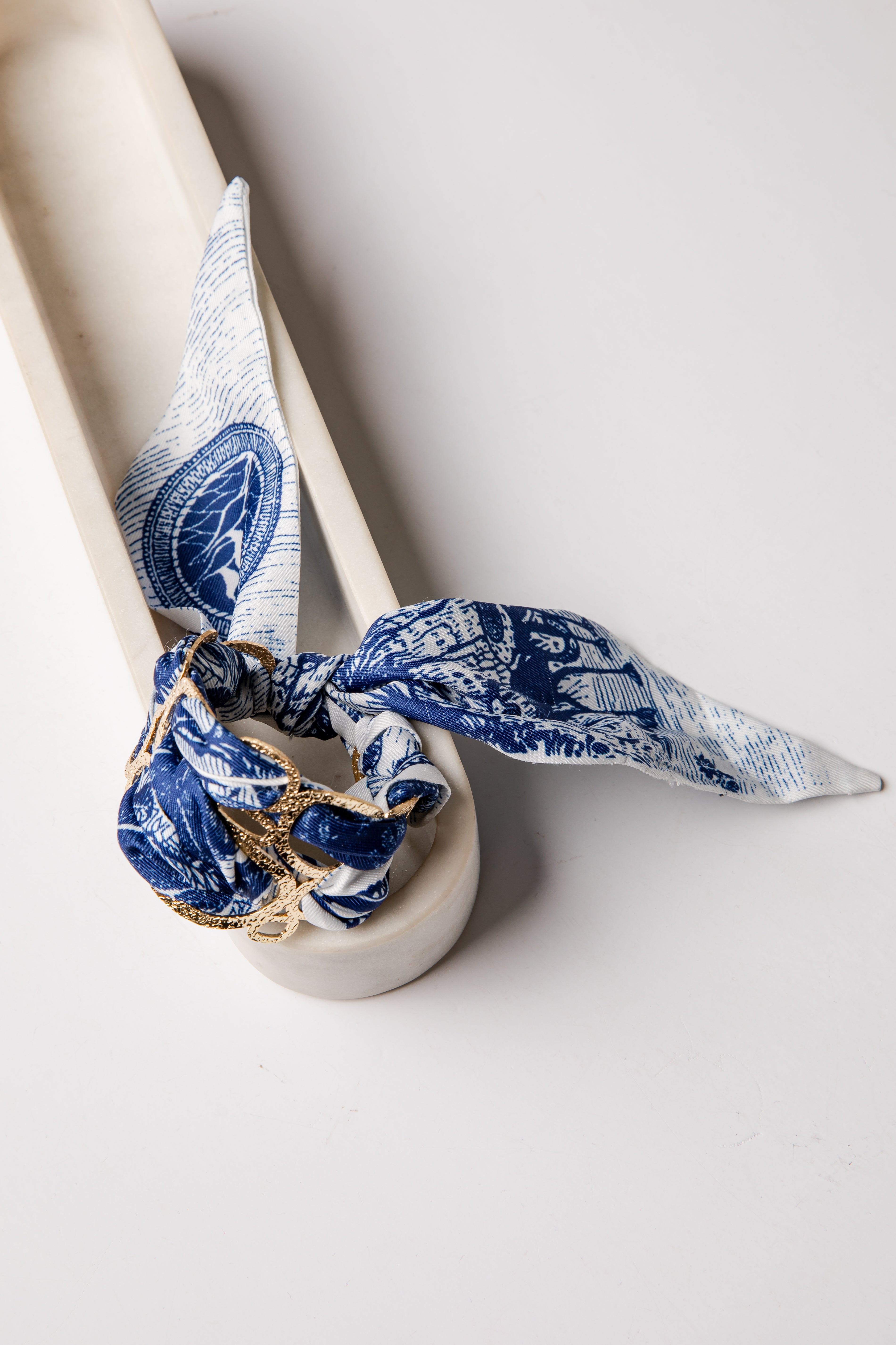 White ceramic with a blue and white patterned cloth tied around it on a light gray background