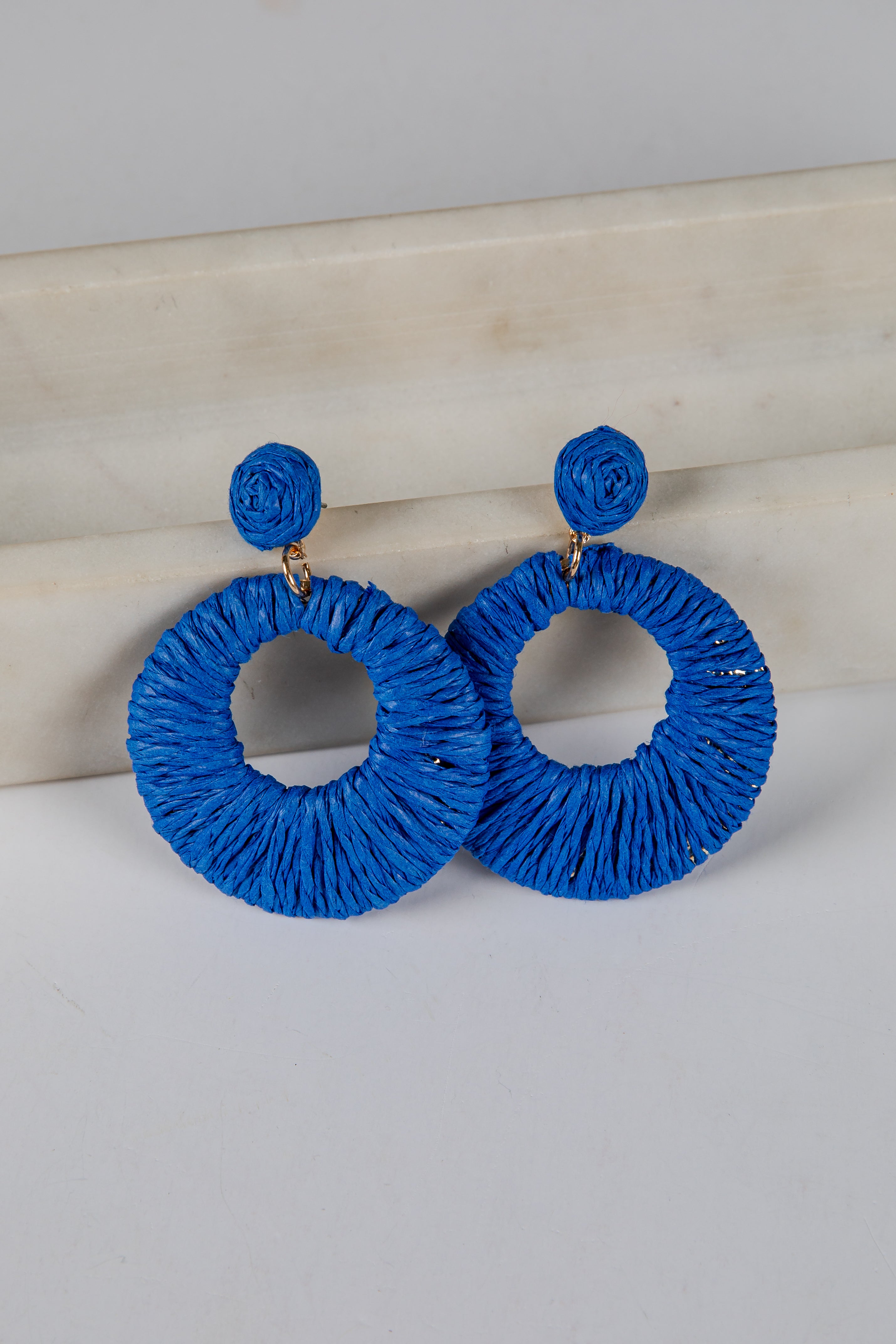 Blue hoop earrings on a light gray surface