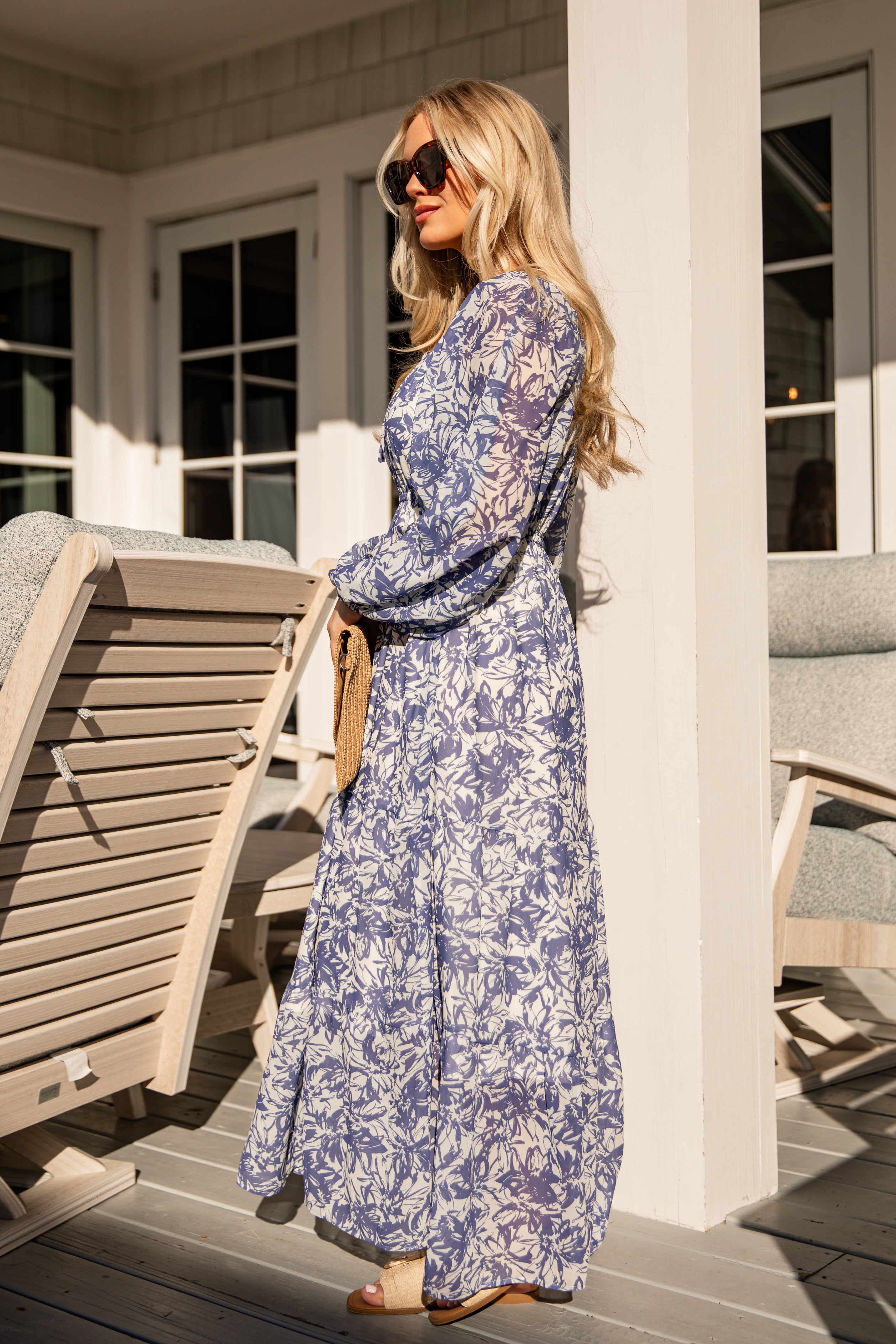 Woman in a blue floral dress standing on a porch