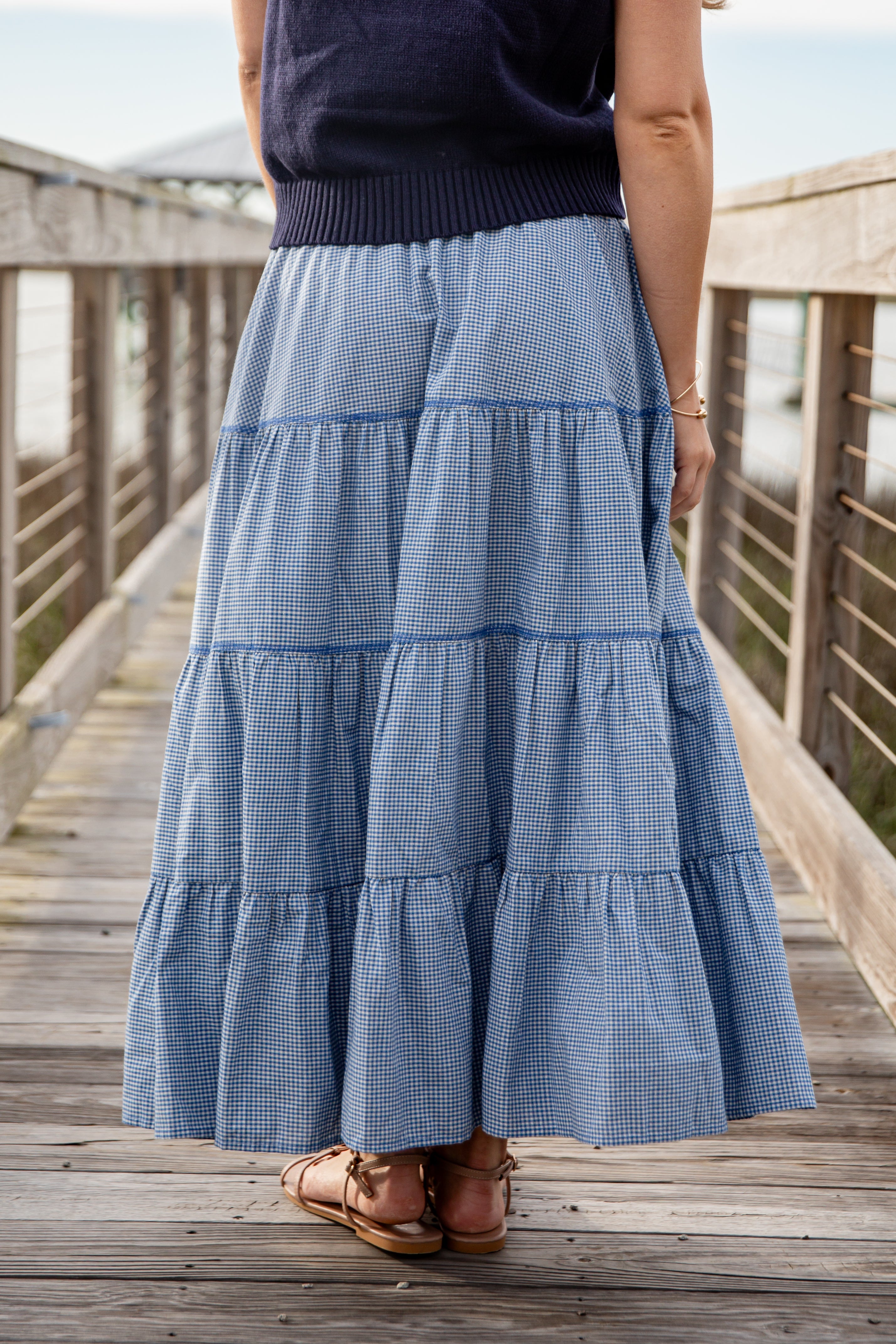 Person wearing a blue tiered skirt on a wooden deck
