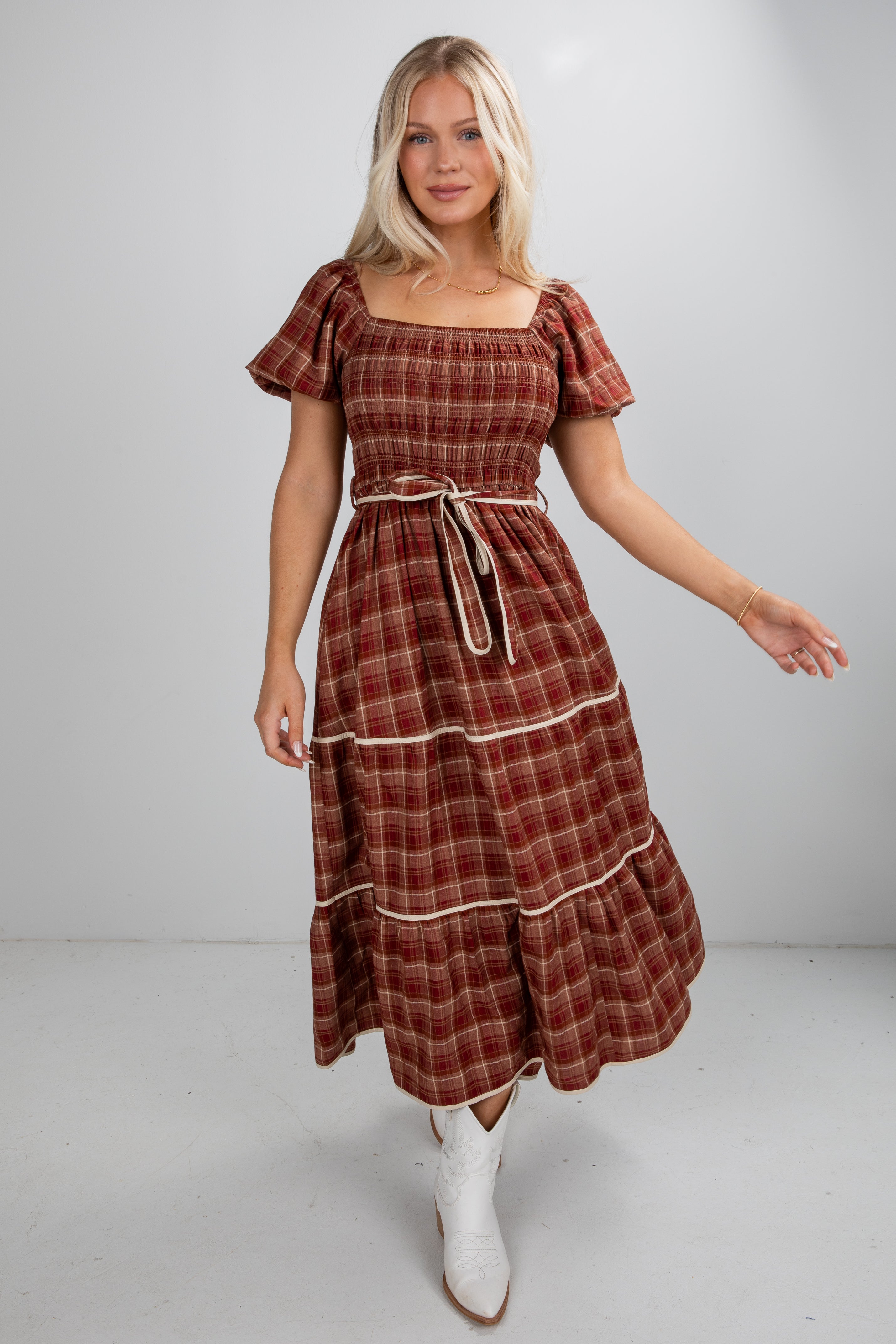 Woman wearing a plaid dress with puff sleeves on a plain background