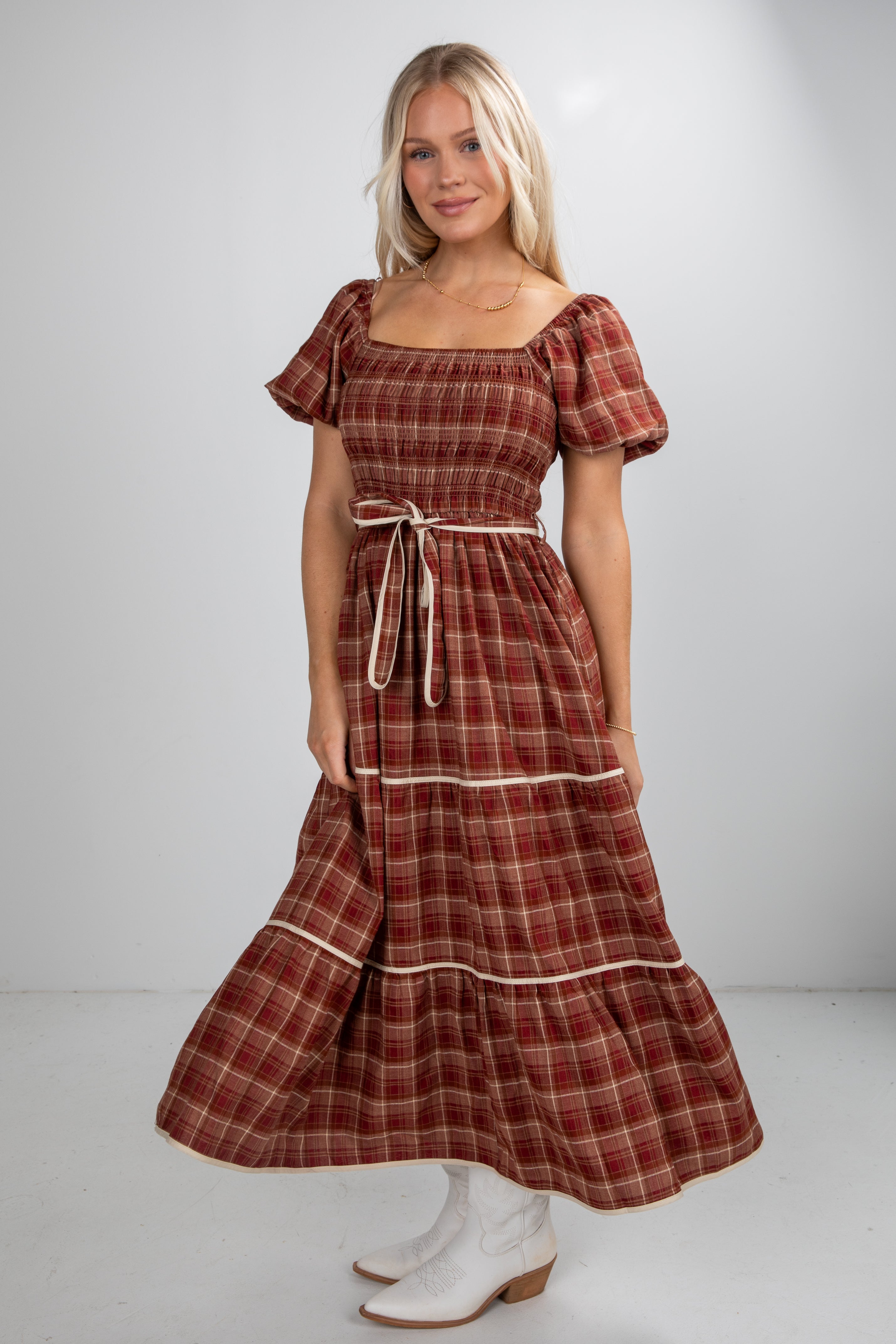 Woman wearing a plaid dress with puff sleeves against a white background