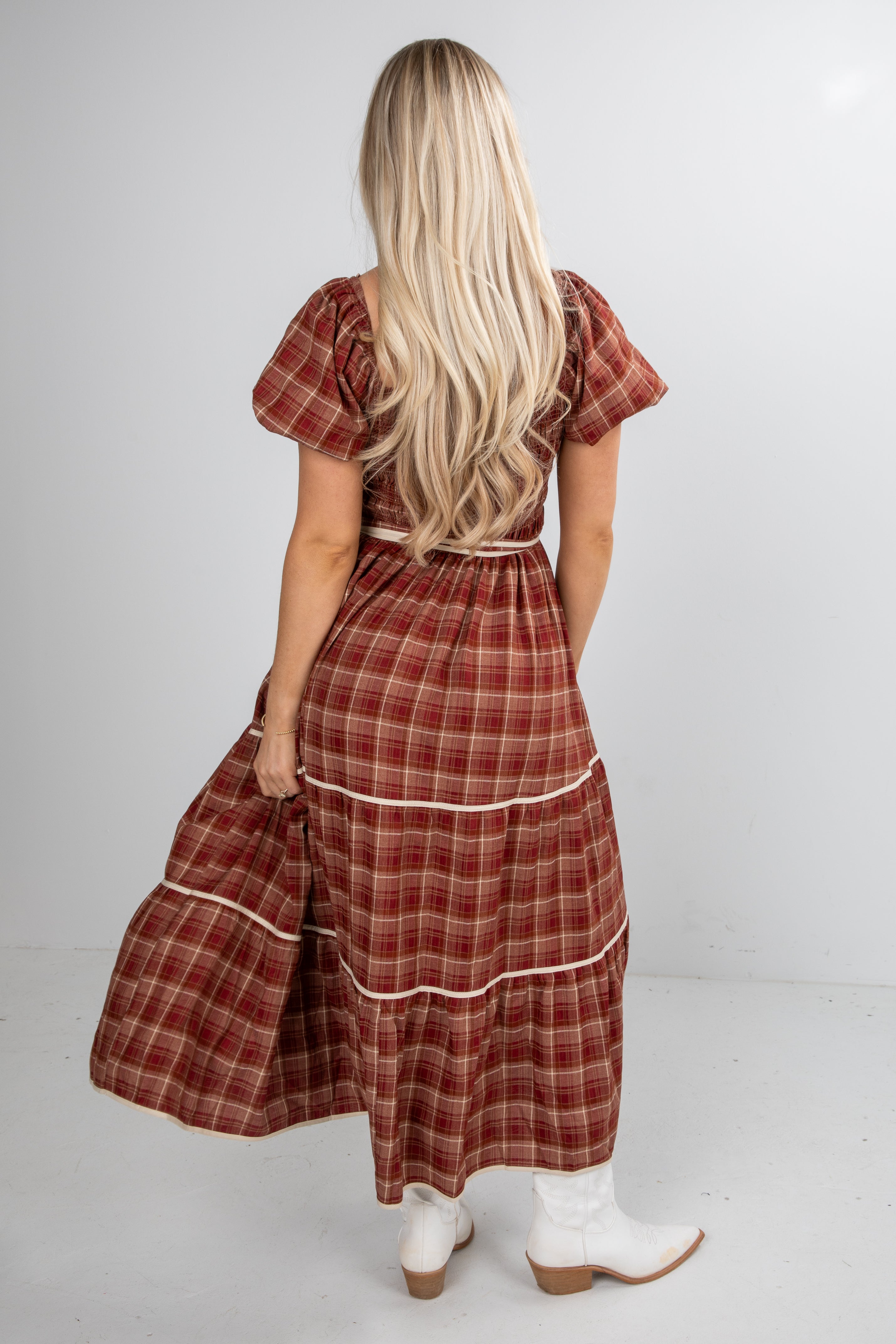 Woman wearing a red plaid dress with white trim on a plain background