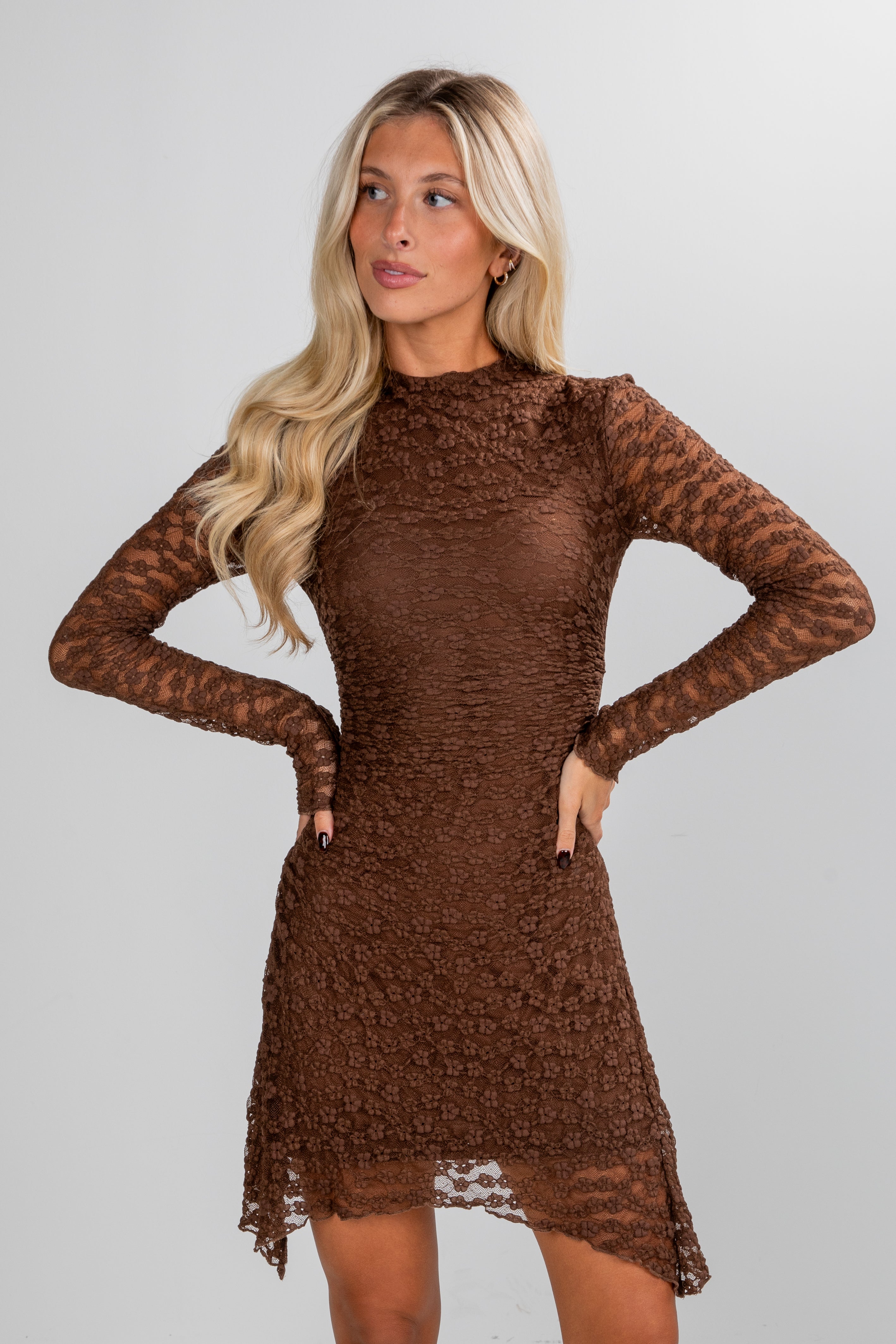 Woman wearing a brown lace dress against a plain background