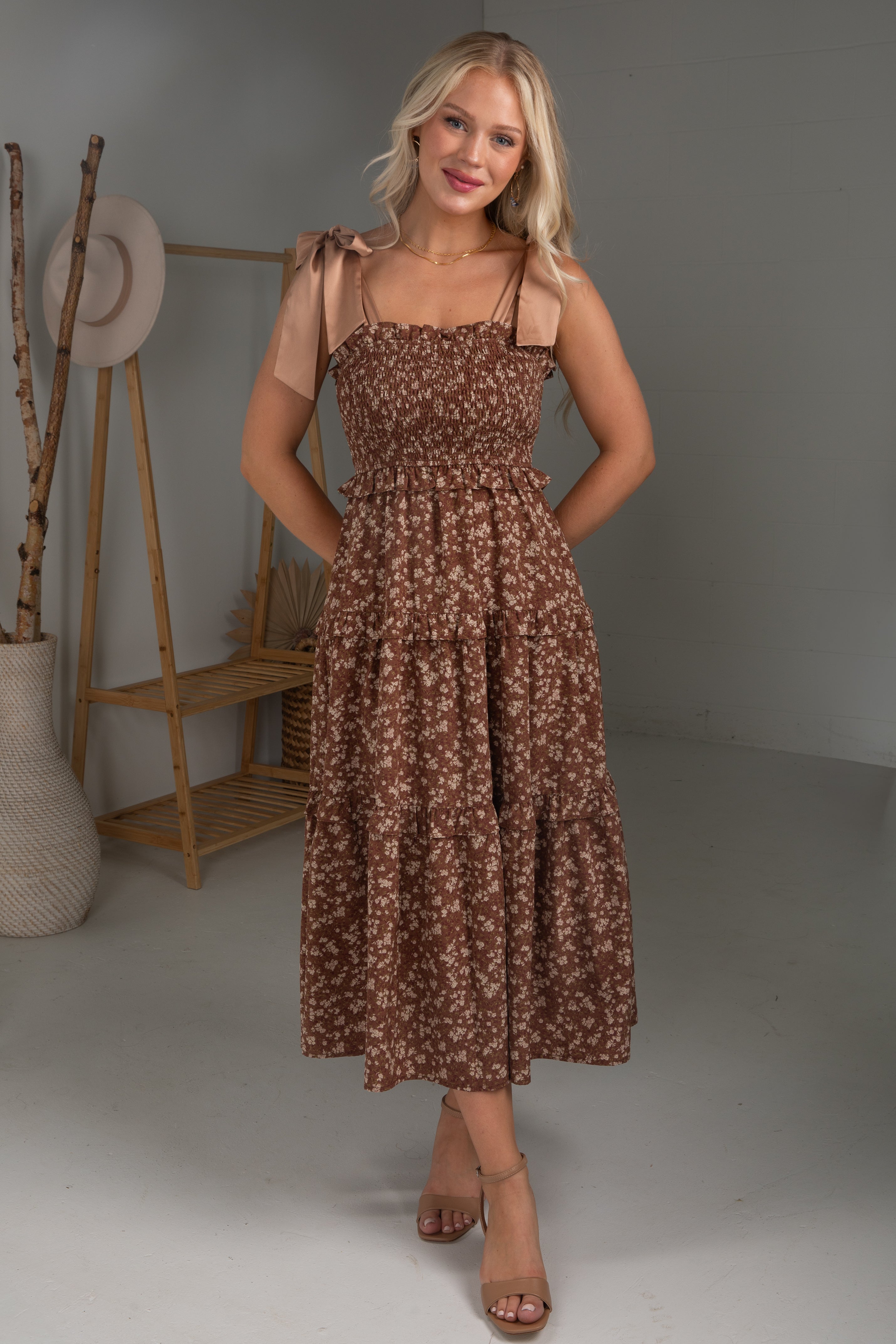 Woman wearing a brown floral dress in a studio setting