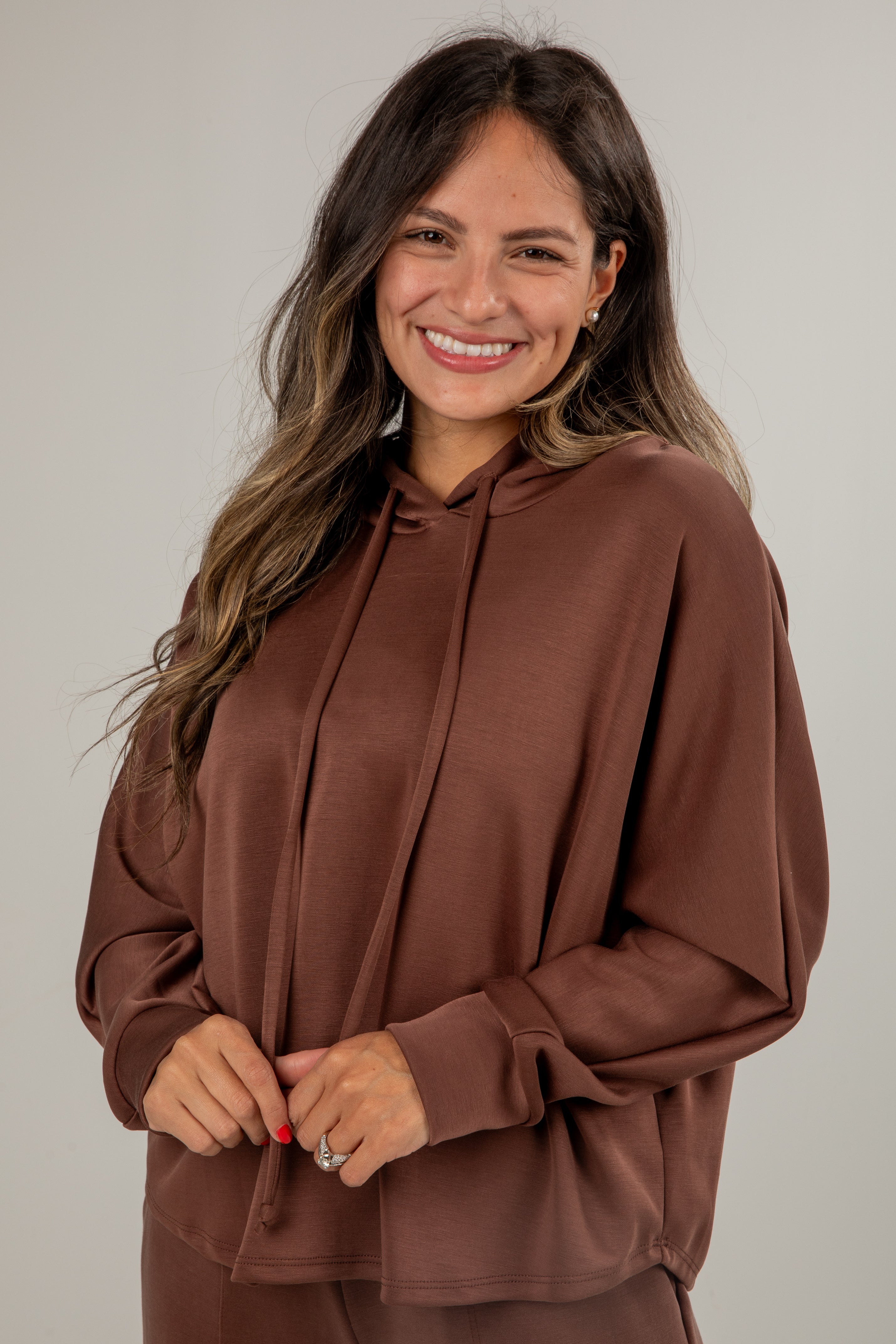 Woman wearing a brown hoodie against a plain background