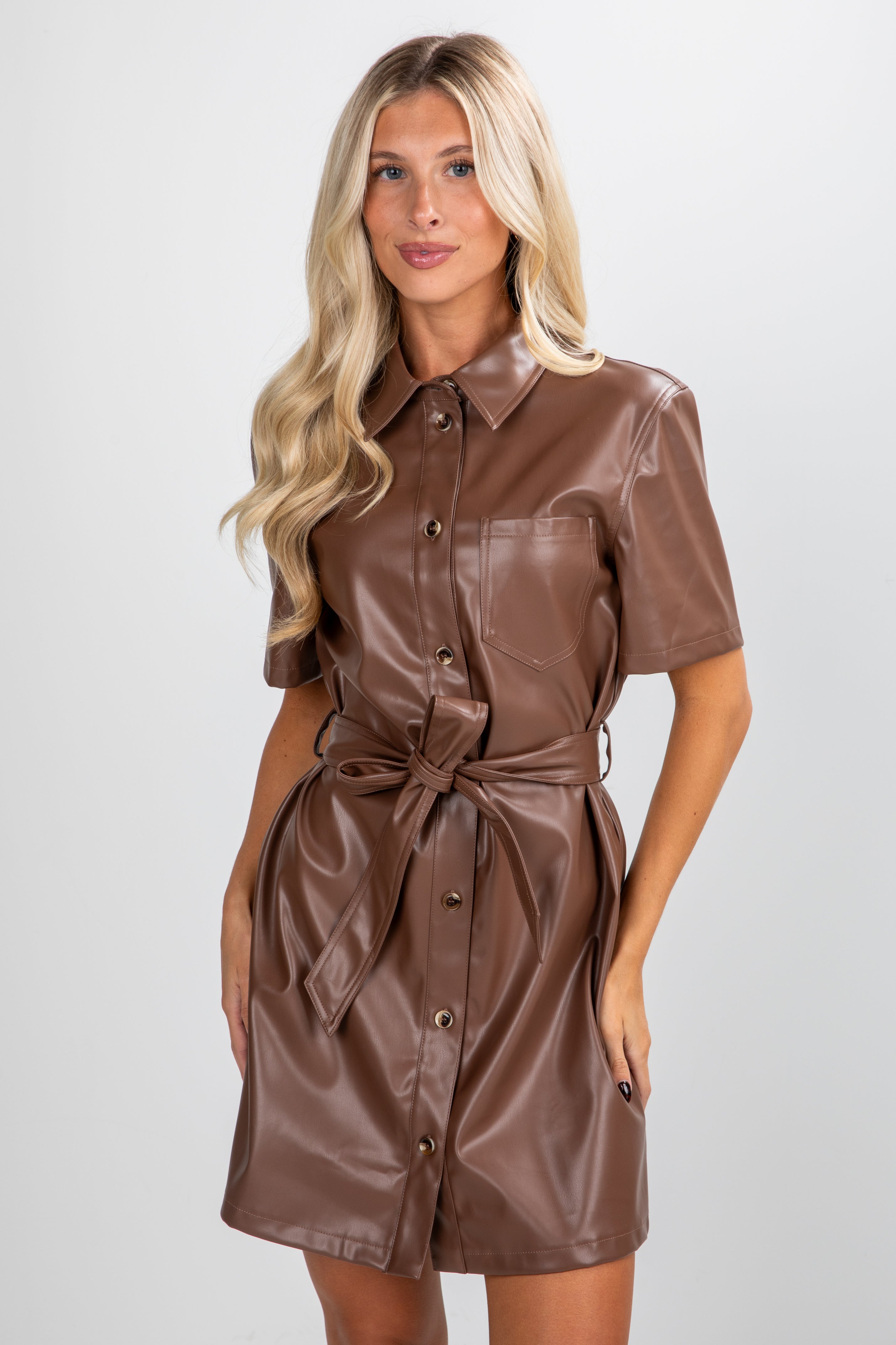 Woman wearing a brown leather dress against a white background